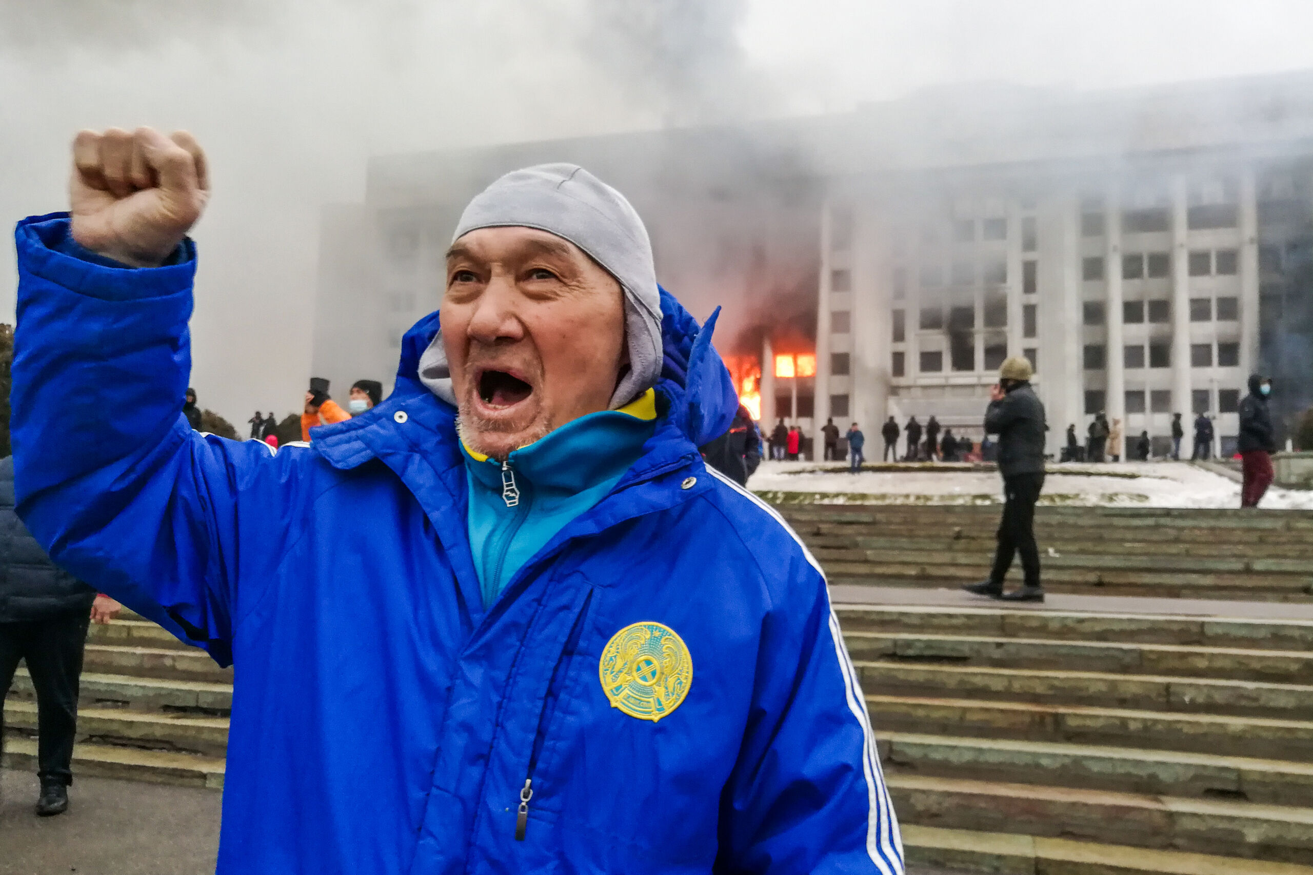 Demonstrant voor het brandende gemeentehuis van Almaty 