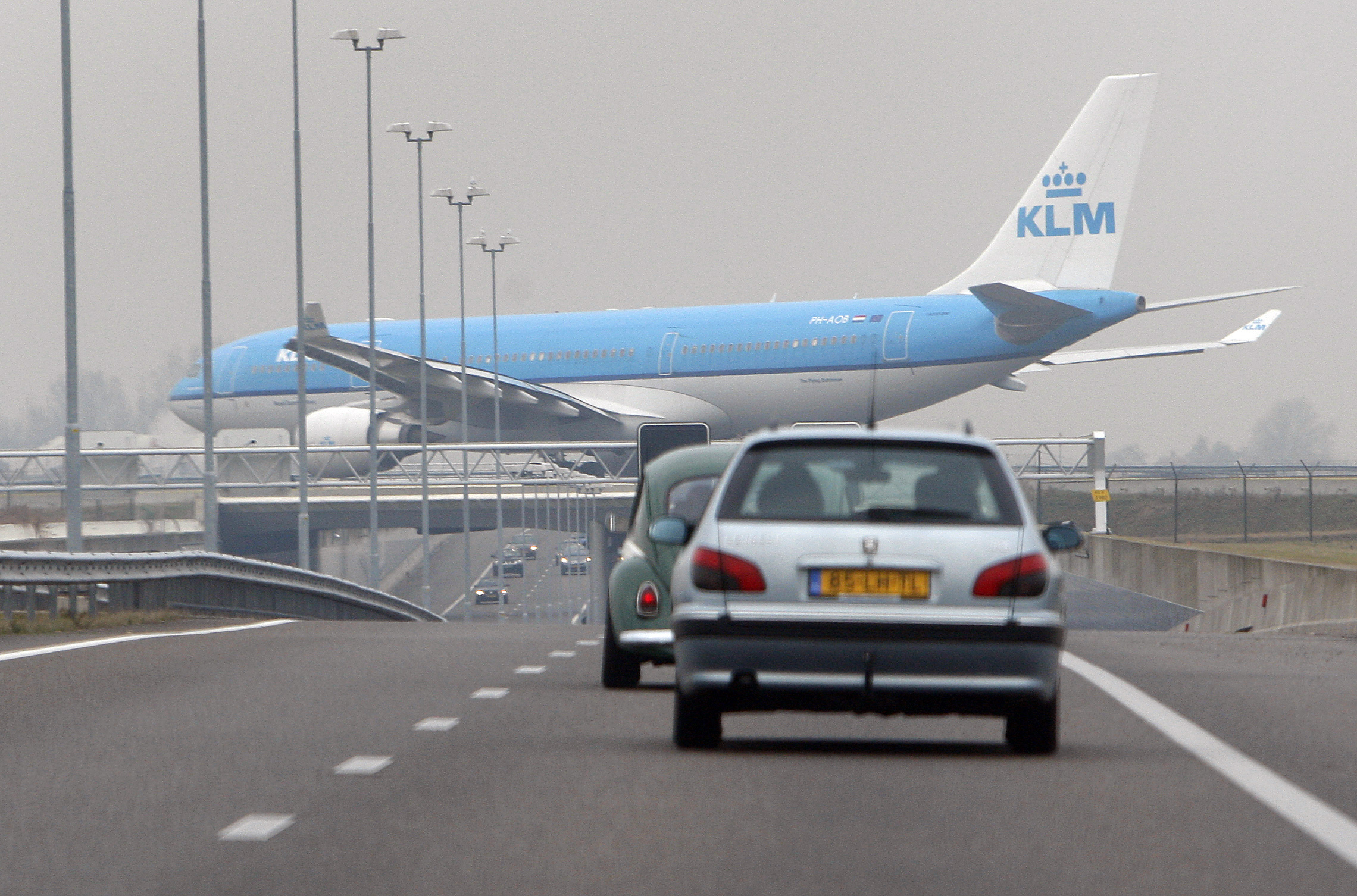 Een KLM-toestel passeert de A5 snelweg. 