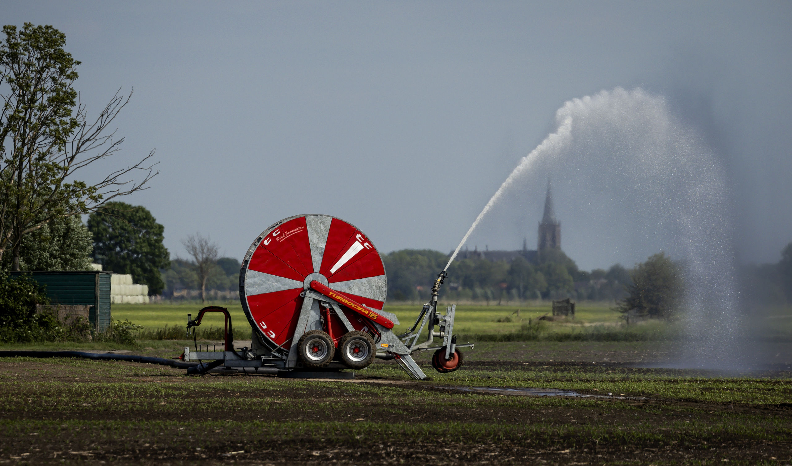 Een boer beregent zijn akker.