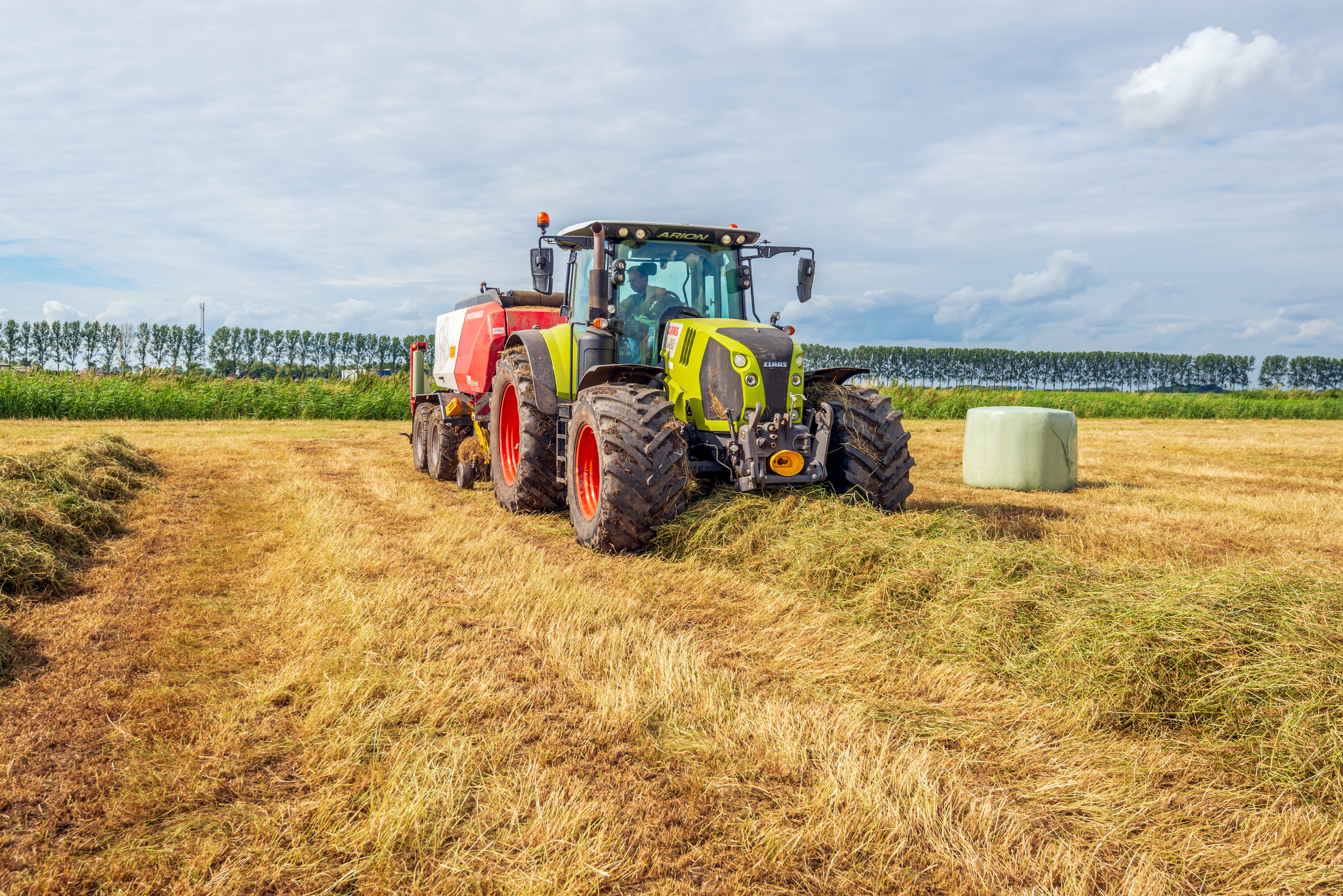 Het hooi wordt verzameld met een combinatiebalenpers en wikkelaar, op rollen geperst en vervolgens omwikkeld met plastic folie.  Hooi dient onder meer als voer voor melkvee tijdens de stalperiode.  De foto is gemaakt in de landelijke omgeving van Etten-Leur, in Noord-Brabant.  ANP / Hollandse Hoogte / Ruud Morijn