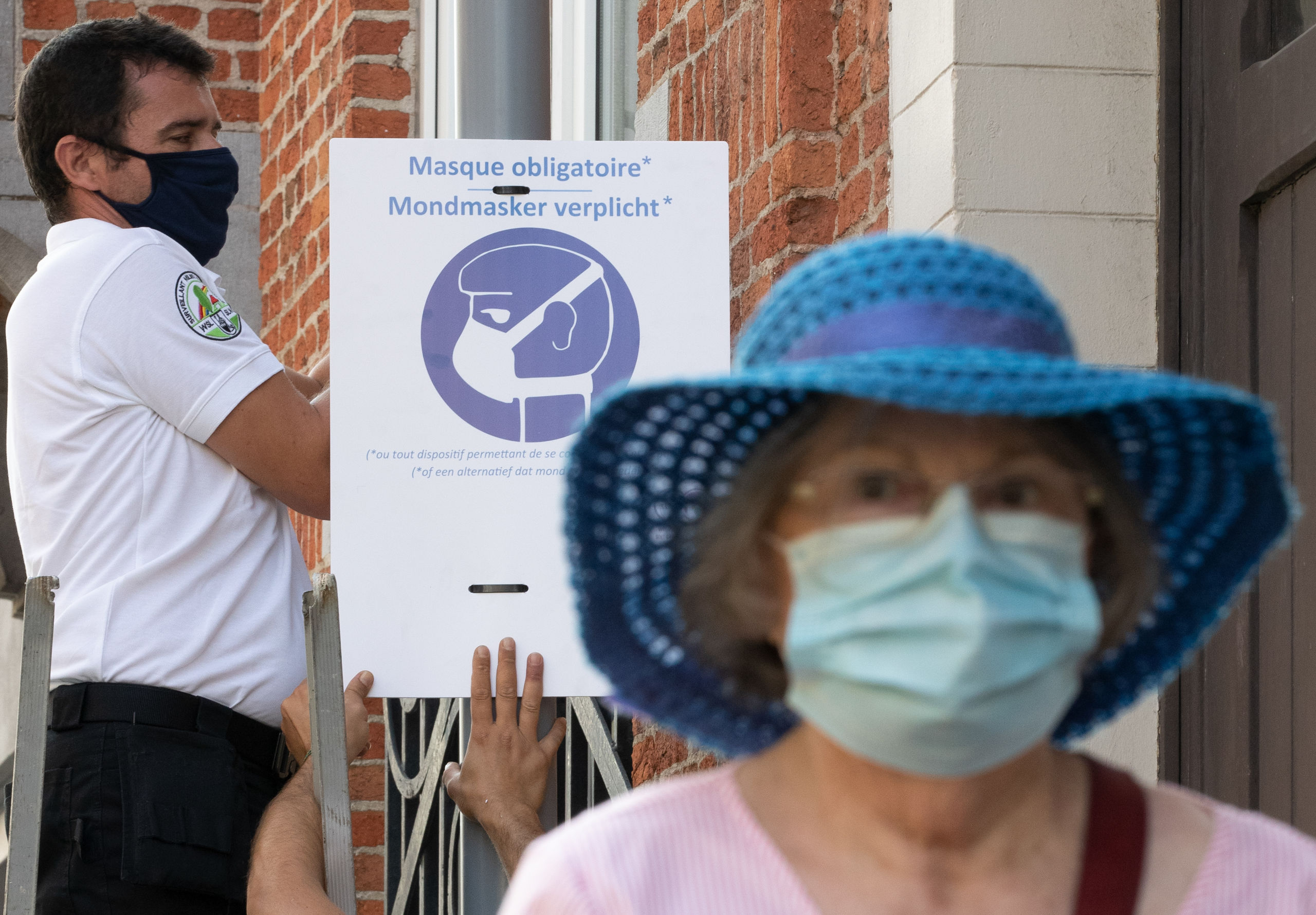 Stadswerkers hangen waarschuwingen om mondkapjes te dragen op in Woluwe-Saint-Lambert in de regio Brussel.