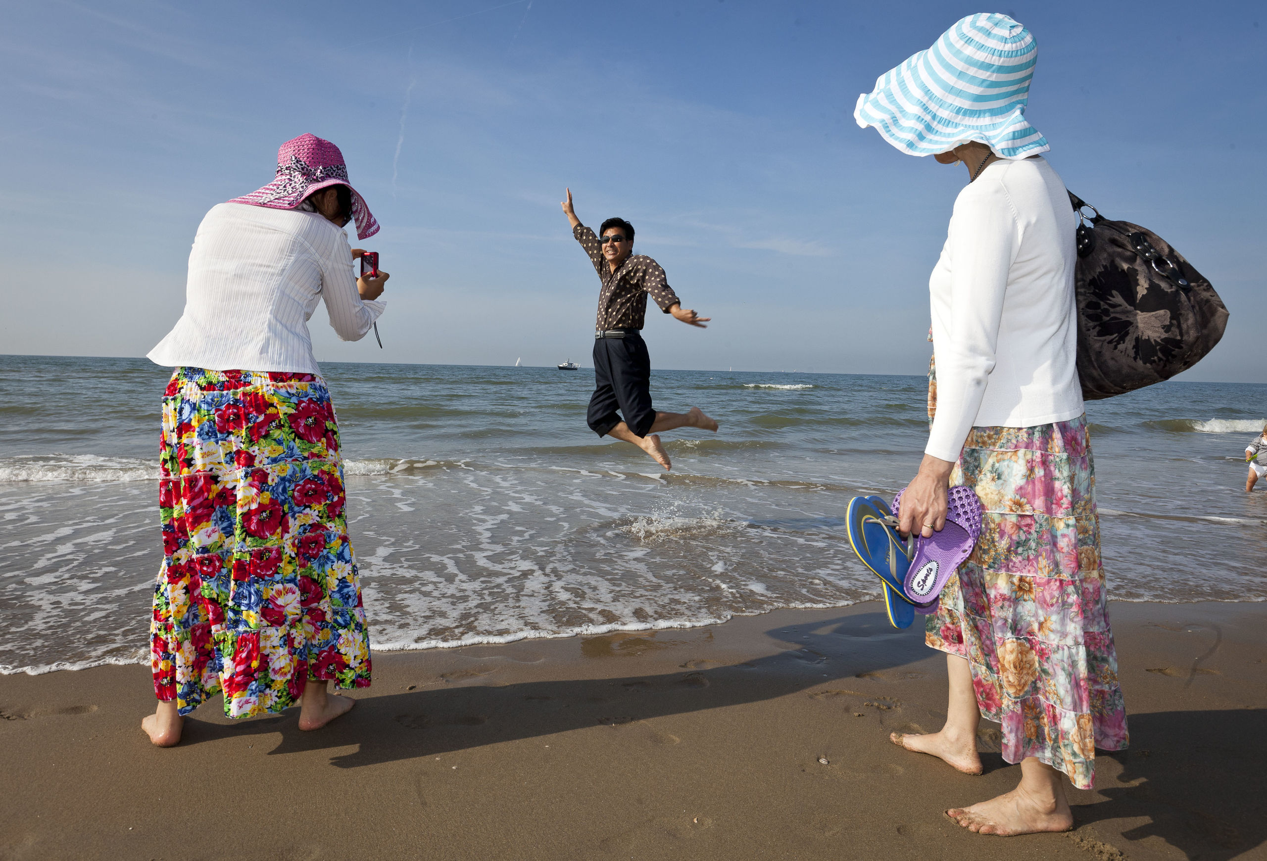 Chinese toeristen genieten van het mooie weer op het strand in Scheveningen 