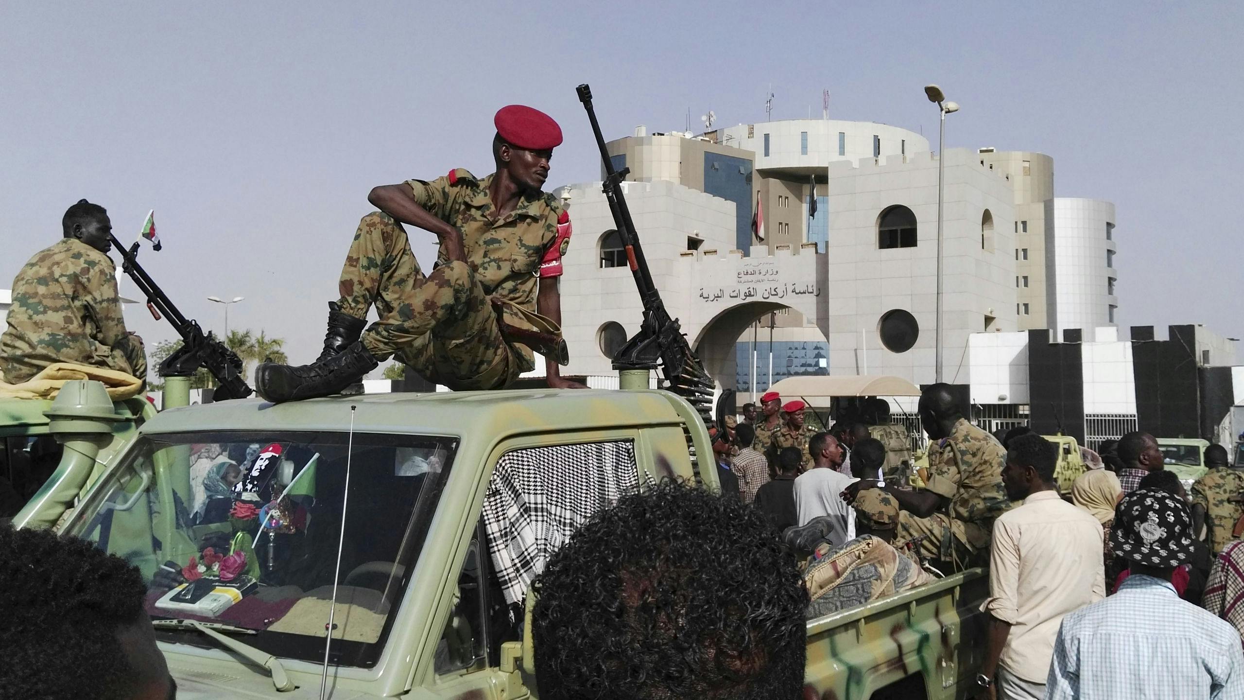 Soedanese soldaten kijken hoe een menigte zich verzamelt in een straat in Khartoem, de hoofdstad van Soedan.