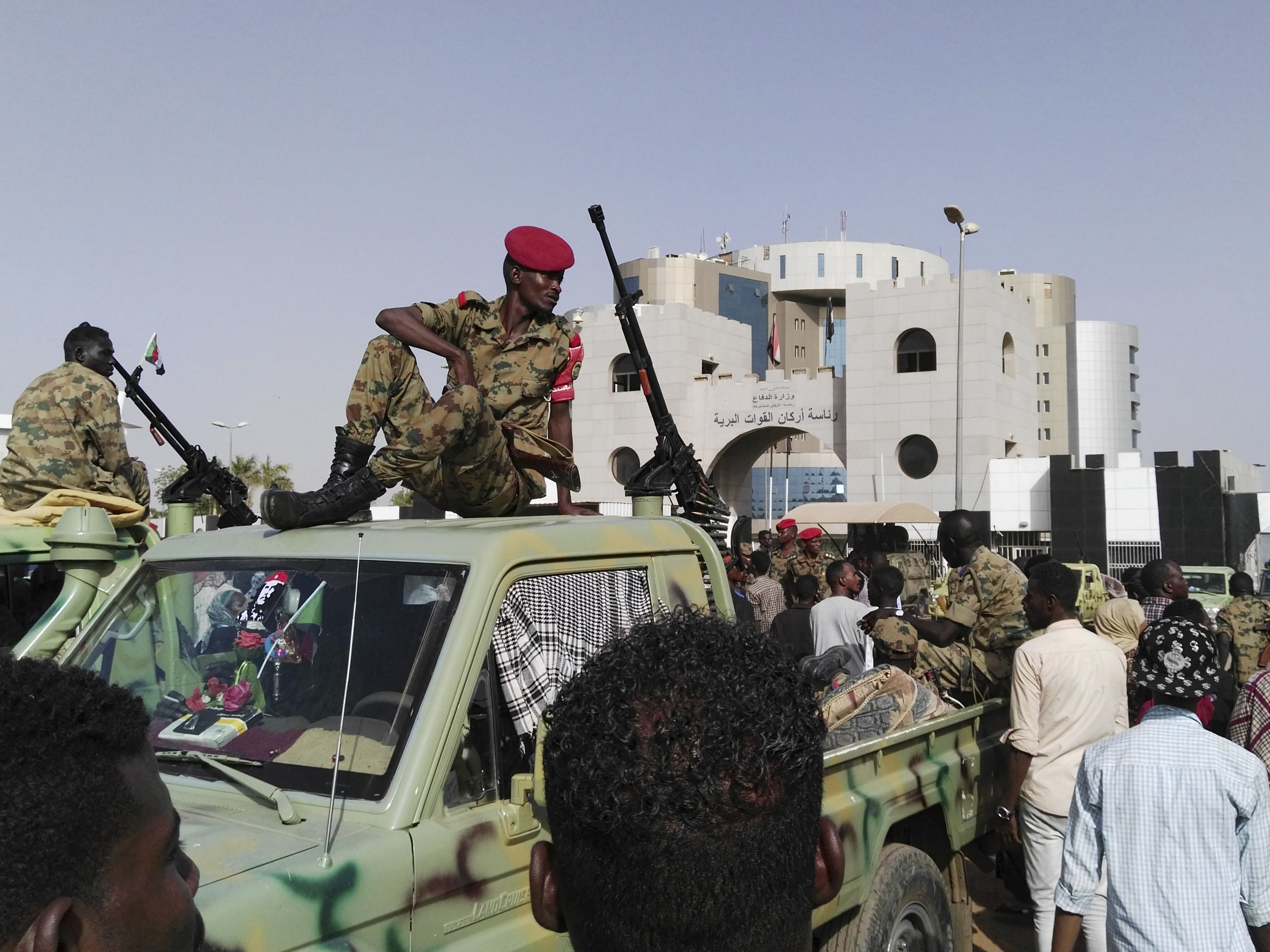 Soedanese soldaten kijken hoe een menigte zich verzamelt in een straat in Khartoem, de hoofdstad van Soedan.
