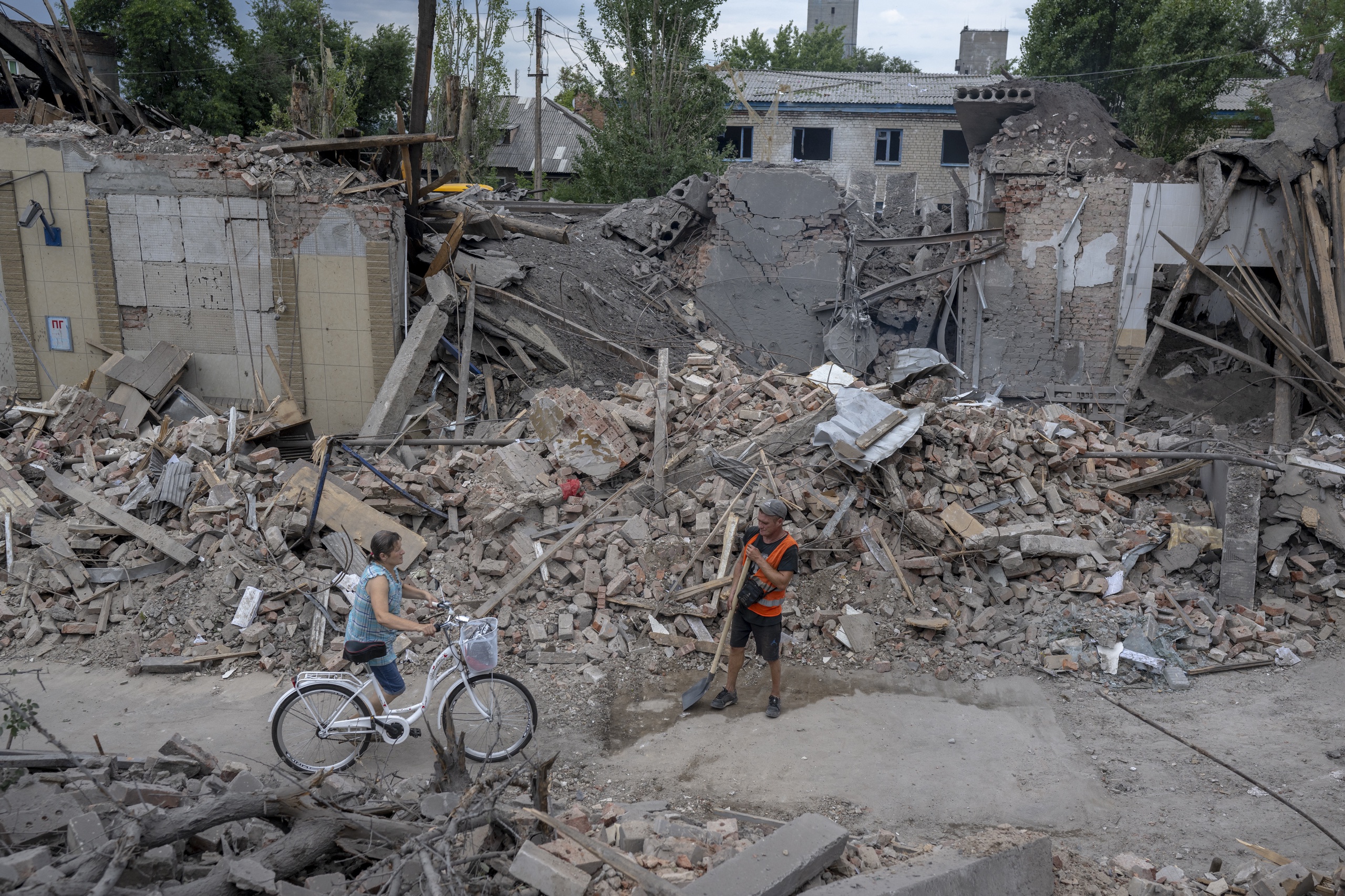 Een inwoner duwt haar fiets door de beschadigde gebouwen in Toretsk in Oost-Oekraïne.