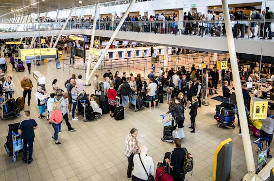 Reizigers in de vertrekhal van Schiphol op de drukste dag van het jaar voor de luchthaven.