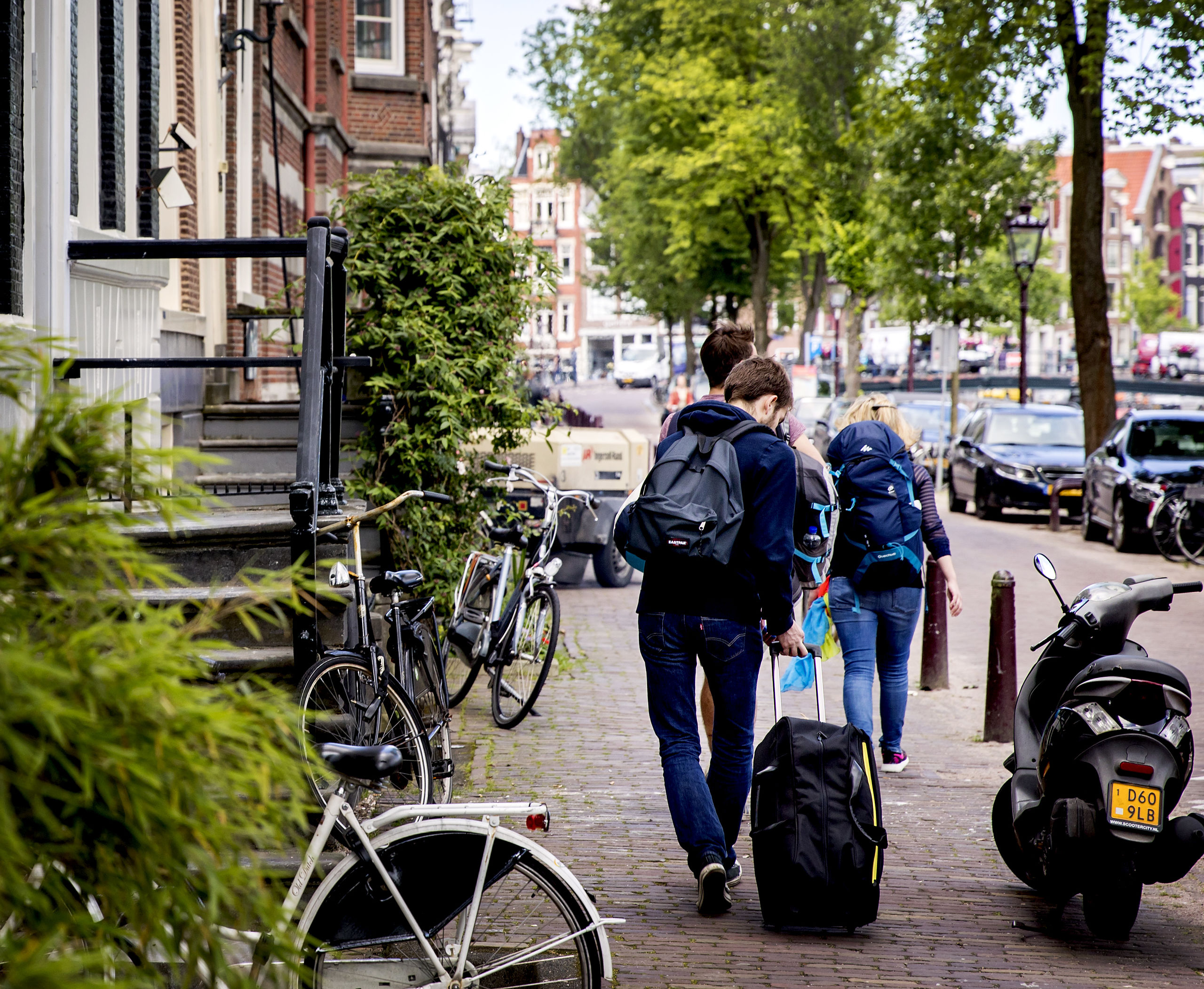 Toeristen met rolkoffers op de grachten in Amsterdam. 