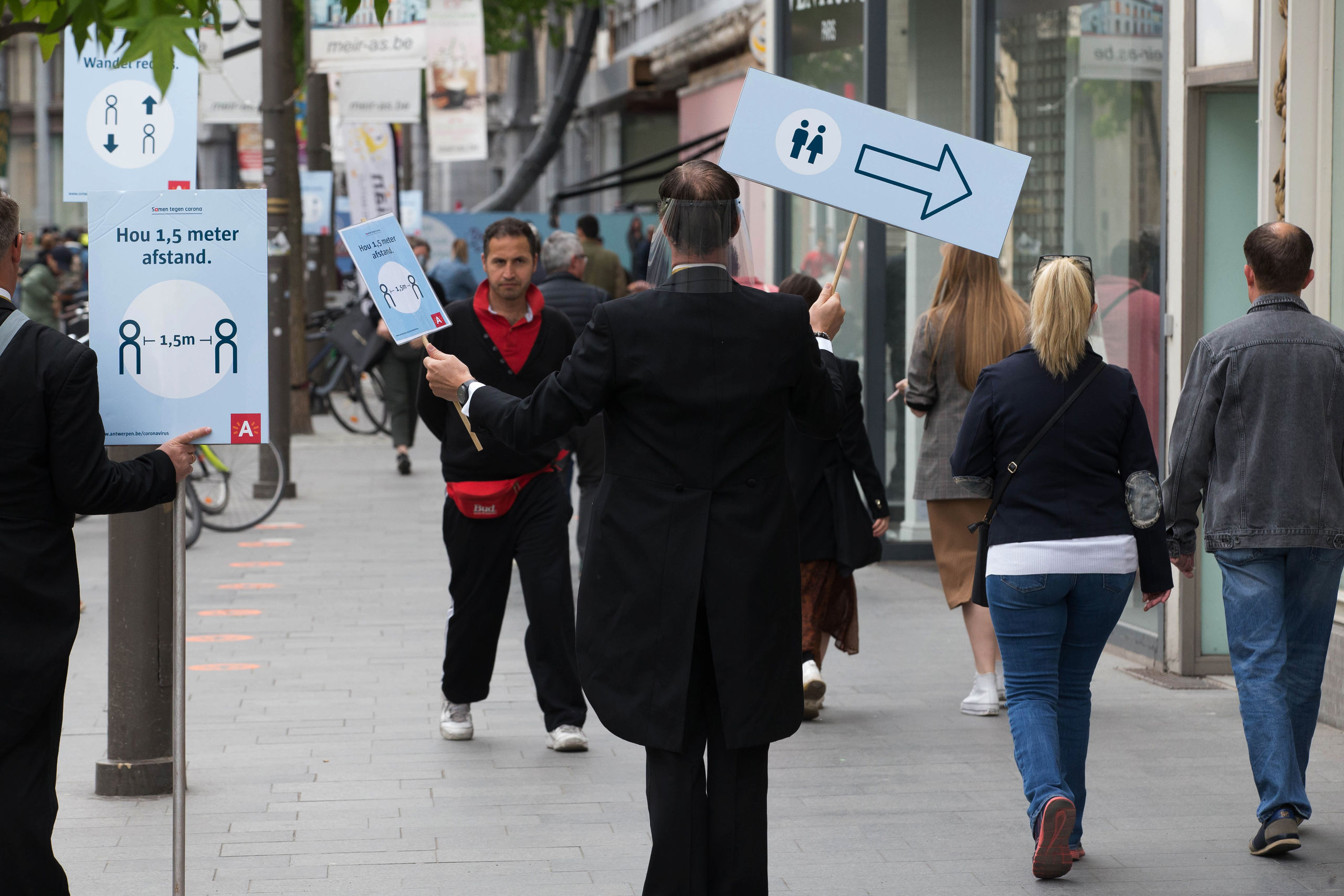 2020-05-16 02:00:00 People hold placards during an action to explain social distancing rules at the Meir shopping street in the city centre of Antwerp on May 16, 2020, as Belgium eases lockdown measures taken to curb the spread of the COVID-19 pandemic, caused by the novel coronavirus. NICOLAS MAETERLINCK / BELGA / AFP