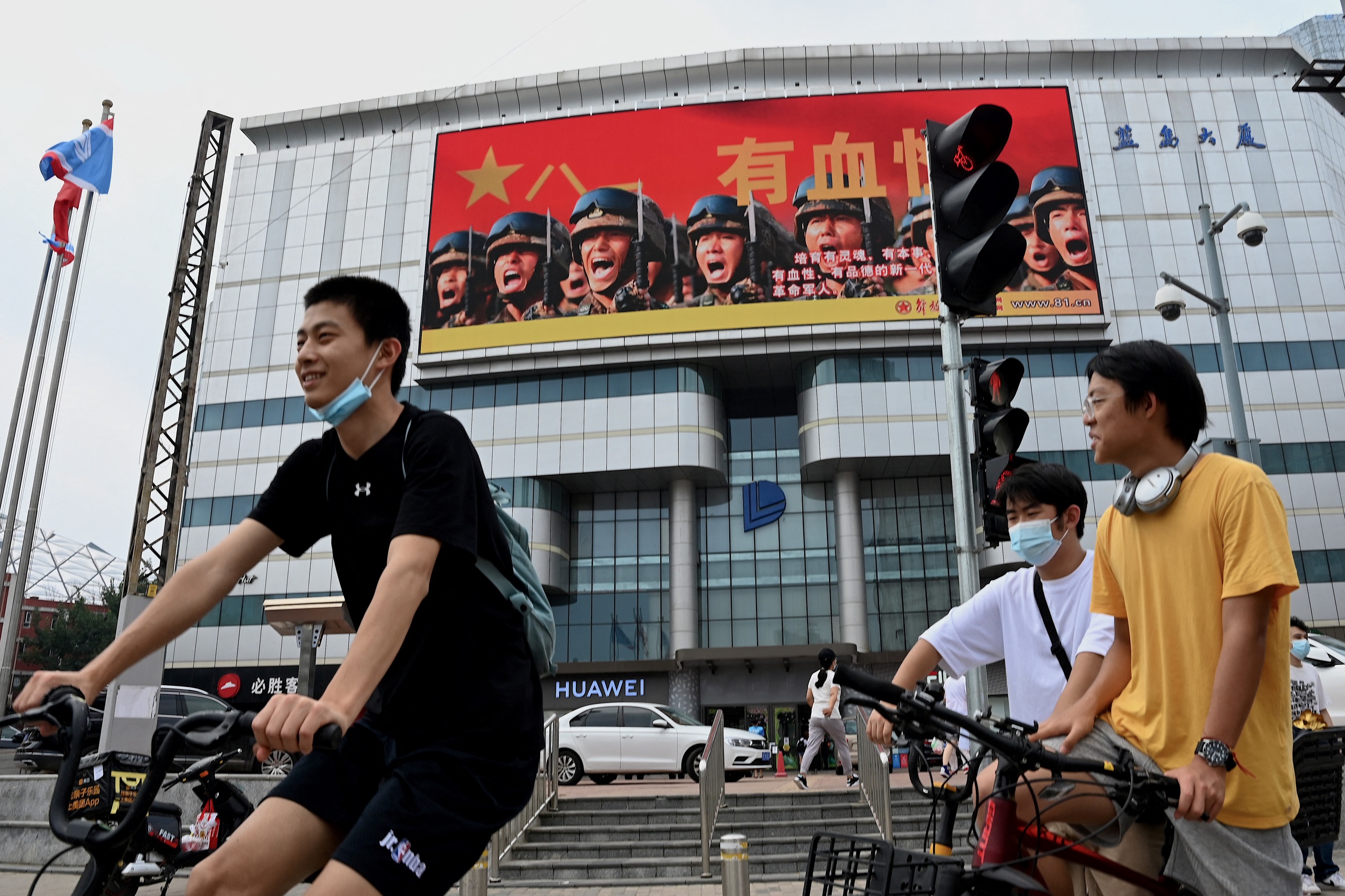 Een groot scherm op een gebouw waarop promotie voor het Chinese Volksbevrijdingsleger (PLA) te zien is, wordt op 4 augustus 2022 door fietsers in Beijing gezien. 