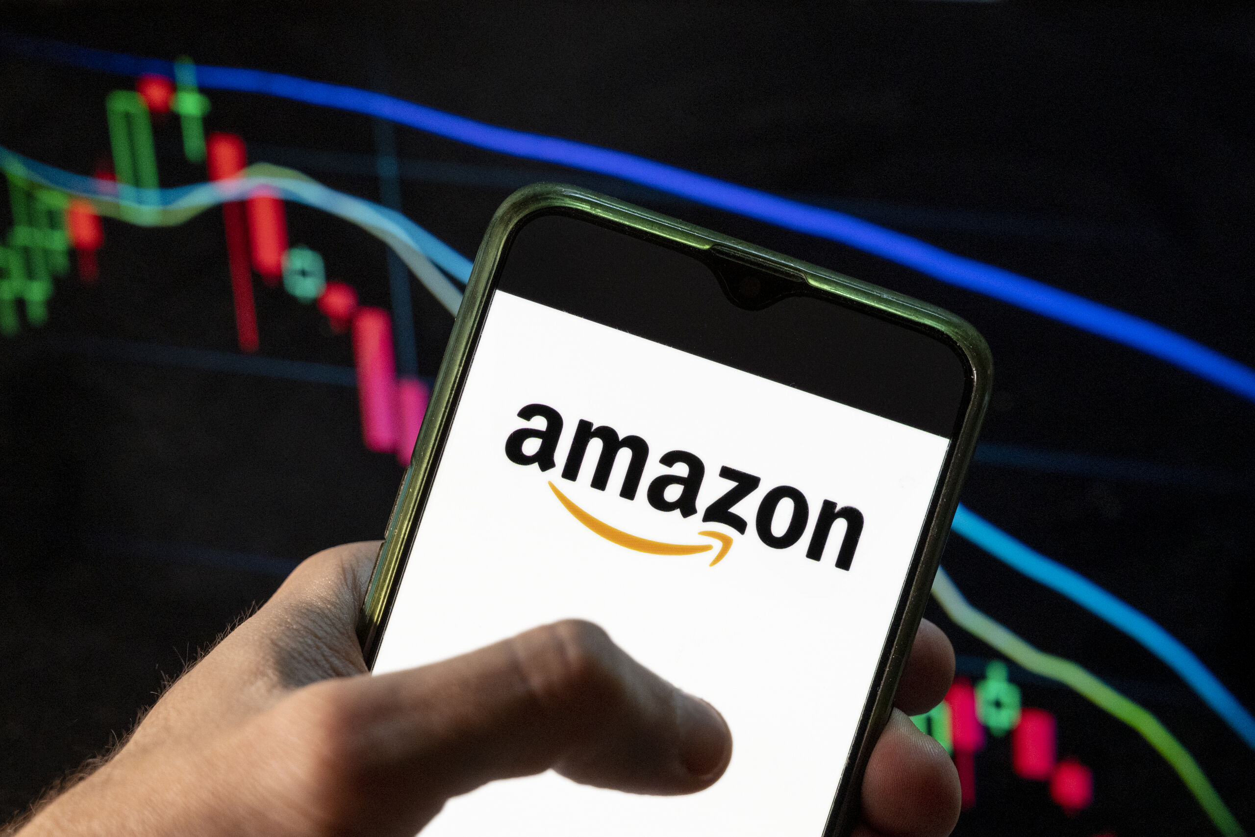 In this photo illustration the American electronic commerce and cloud computing company Amazon logo seen displayed on a smartphone with an economic stock exchange index graph in the background. (Photo by Budrul Chukrut / SOPA Images/Sipa USA)