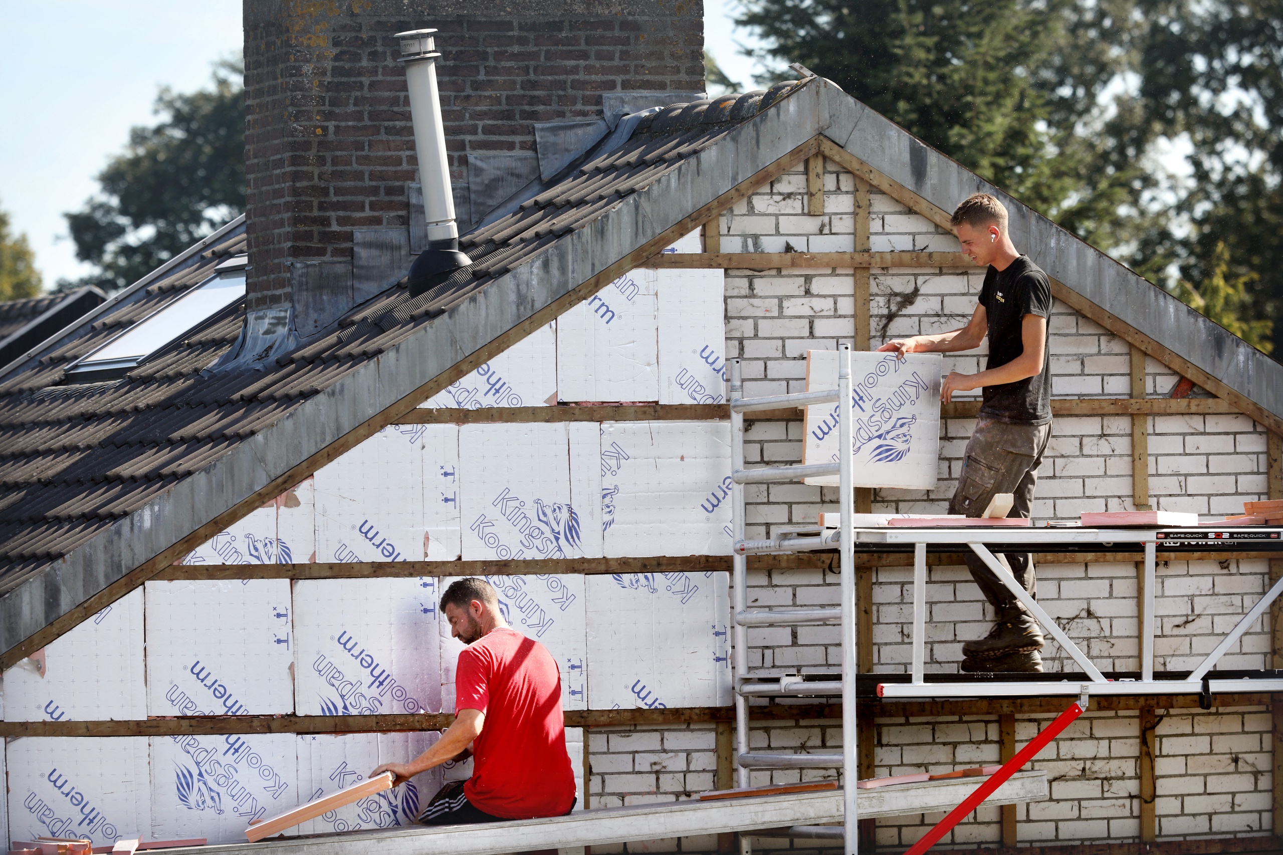 Twee bouwvakkers zijn bezig een bestaande woning te isoleren met PIR platen.