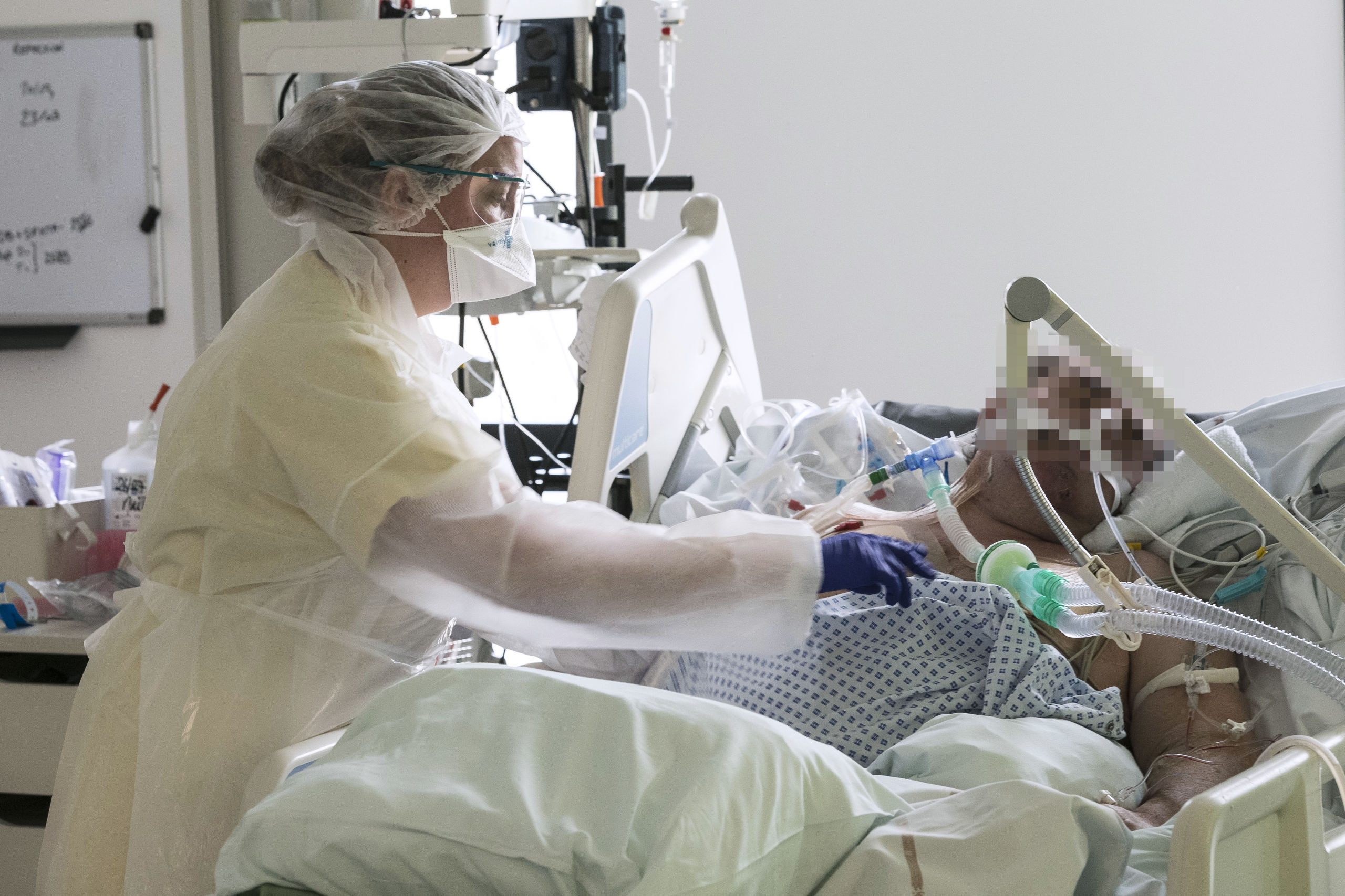Een Franse verpleegkundige verzorgt een patiënt op de intensive care in het Pasteur-ziekenhuis in Colmar, het oosten van Frankrijk.