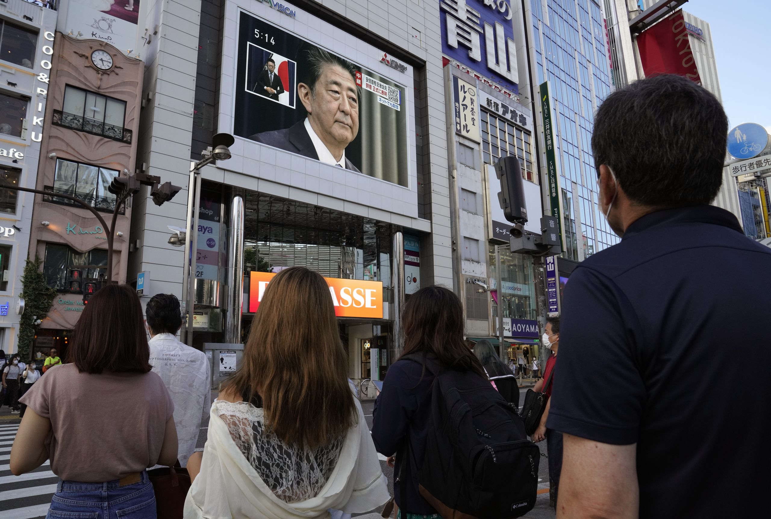 Japanners kijken toe hoe Shinzo Abe zijn afscheid aankondigt.