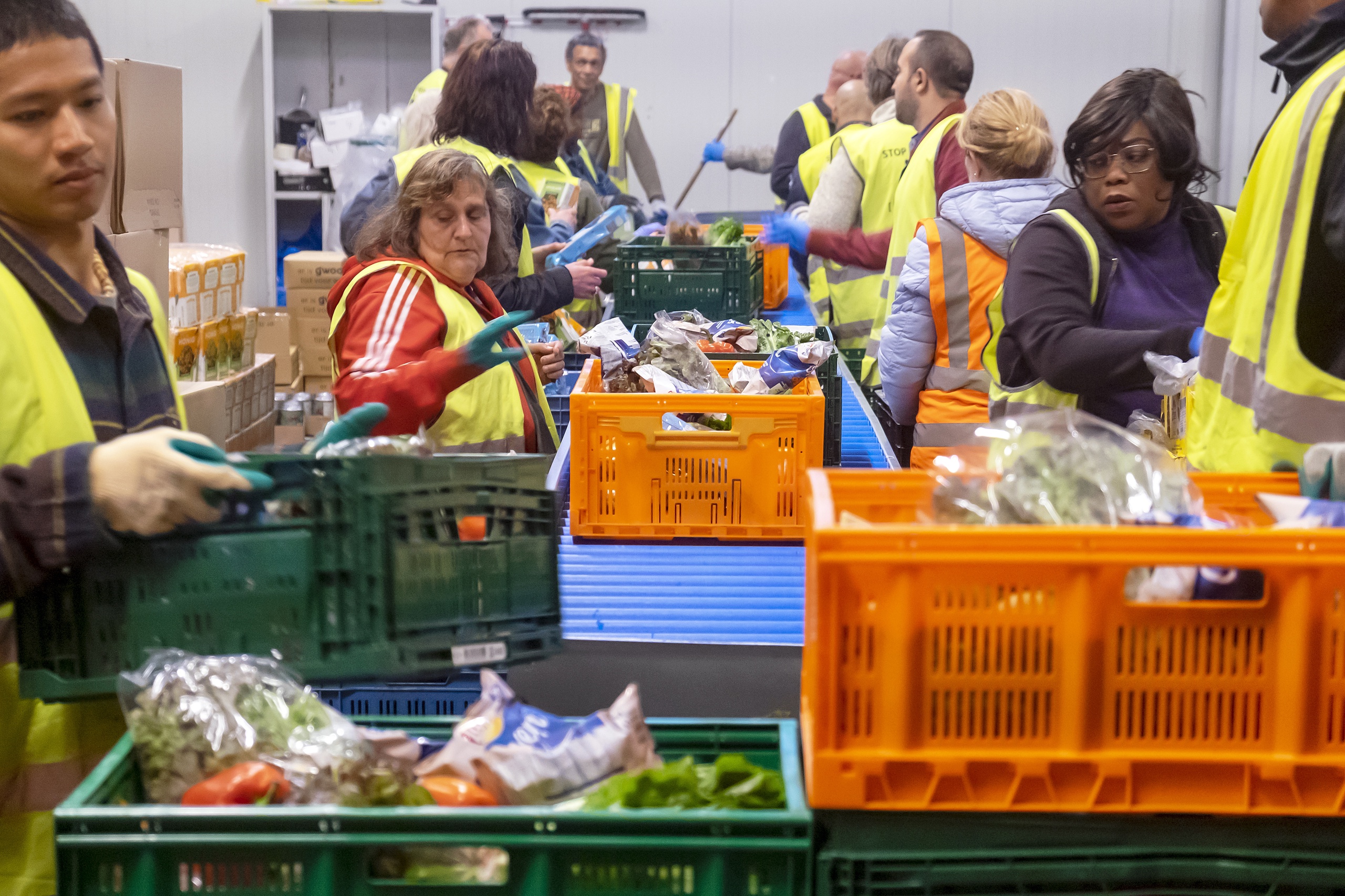 Voedselbank in Rotterdam West Delfshaven. Vrijwilligers, werkelozen en mensen met een licht verstandelijke handicap vullen kratjes met voedsel