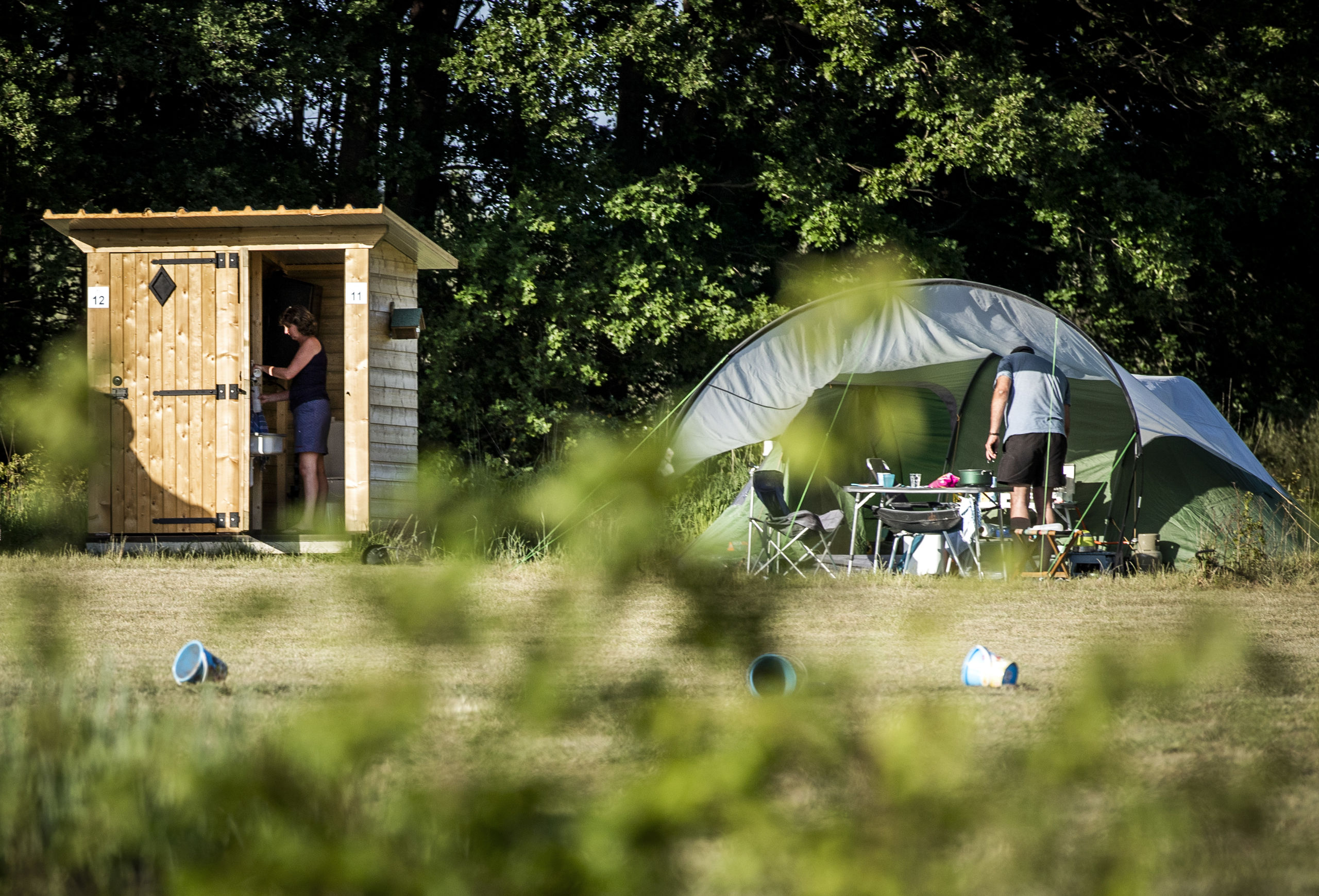 Een houten huisje met privé-sanitair bij de kampeerplek op een camping 