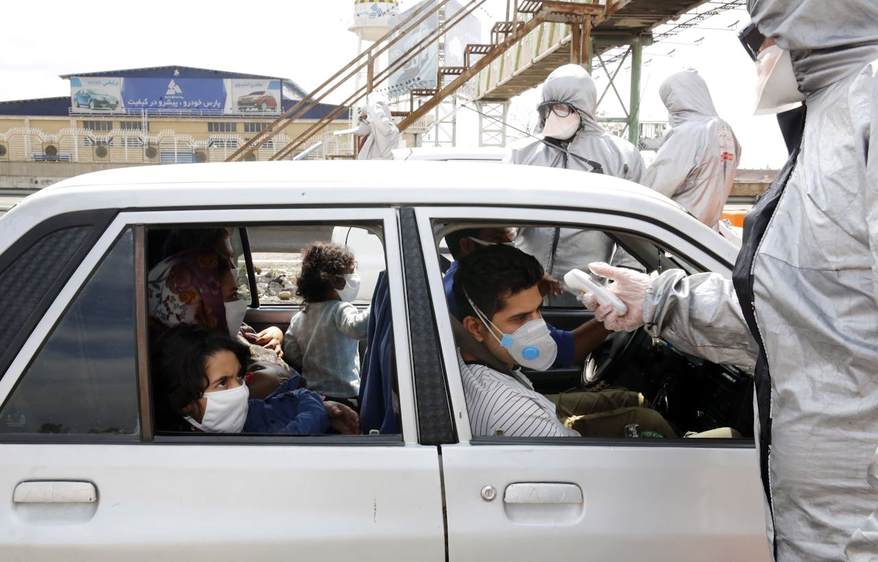 Iraniërs worden in hun auto getest op het coronavirus.