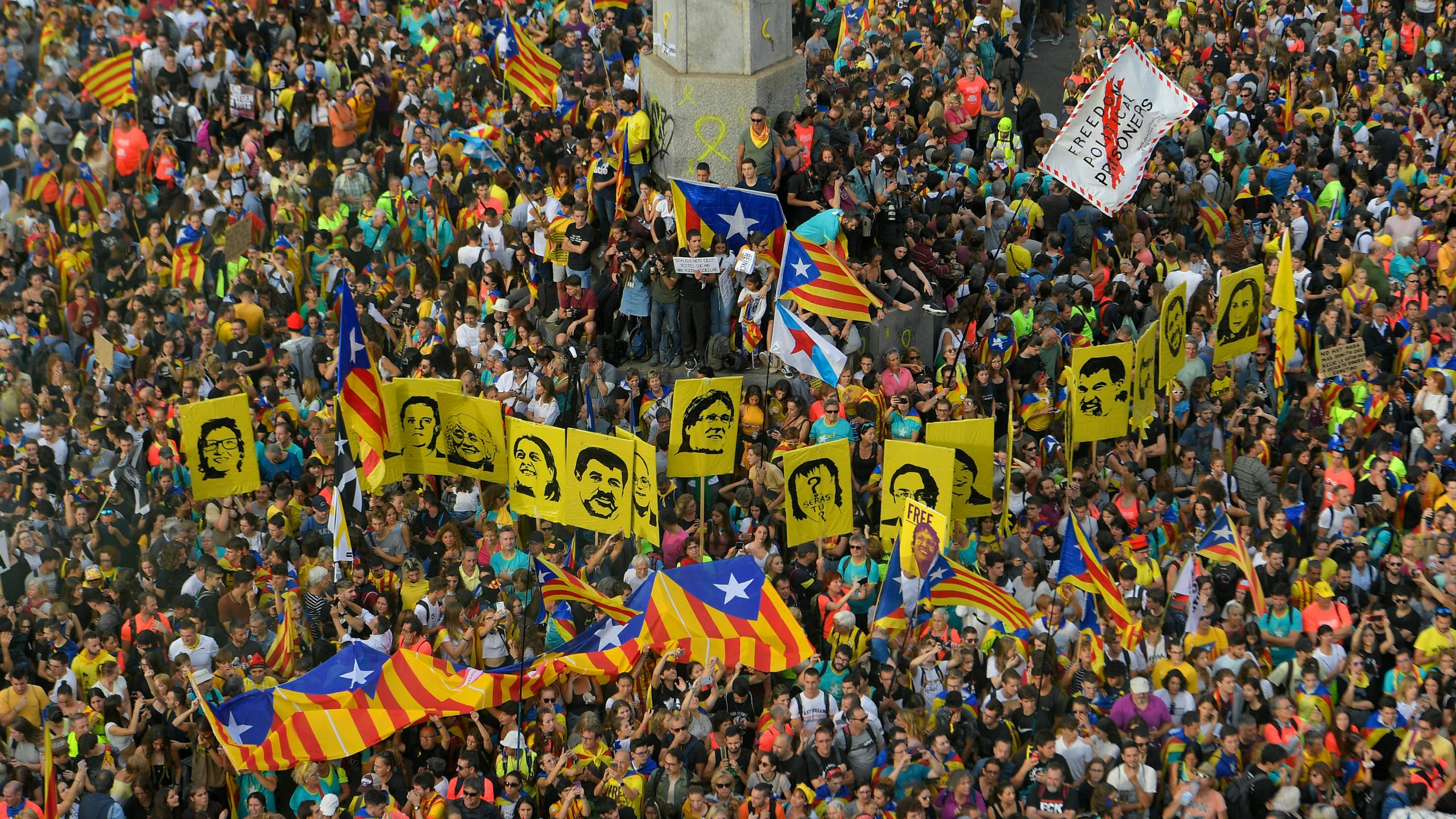 Mensen houden Catalaanse vlaggen en portretten van de separatistische leiders in de lucht tijdens de betoging op 18 oktober 2019.