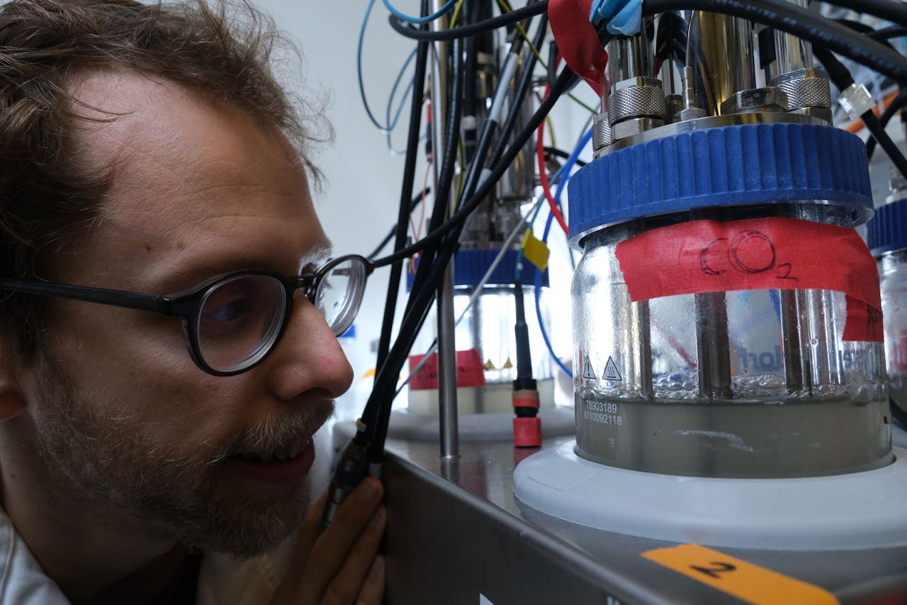 Onderzoekers Nico Claassens bij zijn bioreactor waarin bacteriën groeien op CO2.