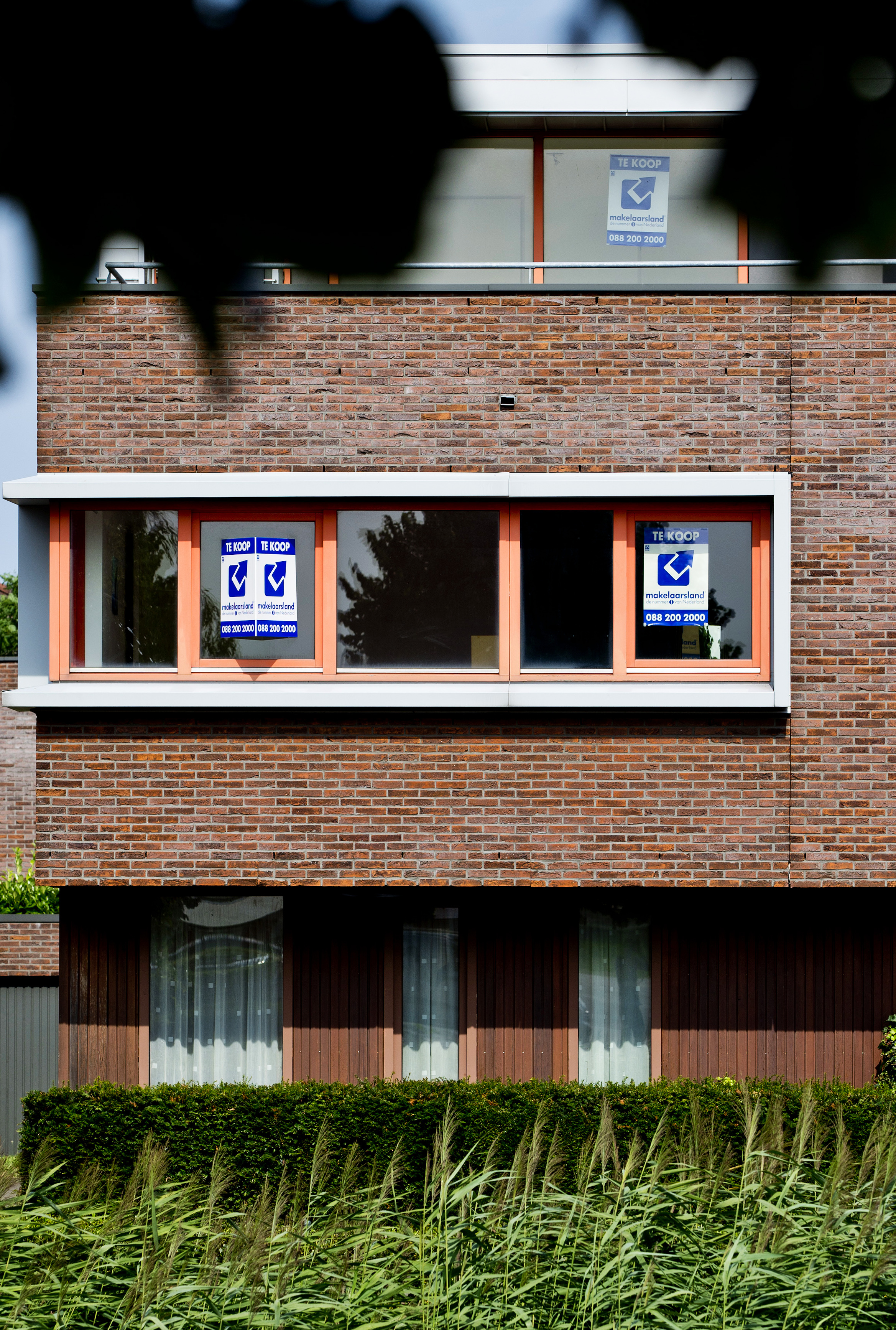 Een verkoopbord aan de gevel van een woning.