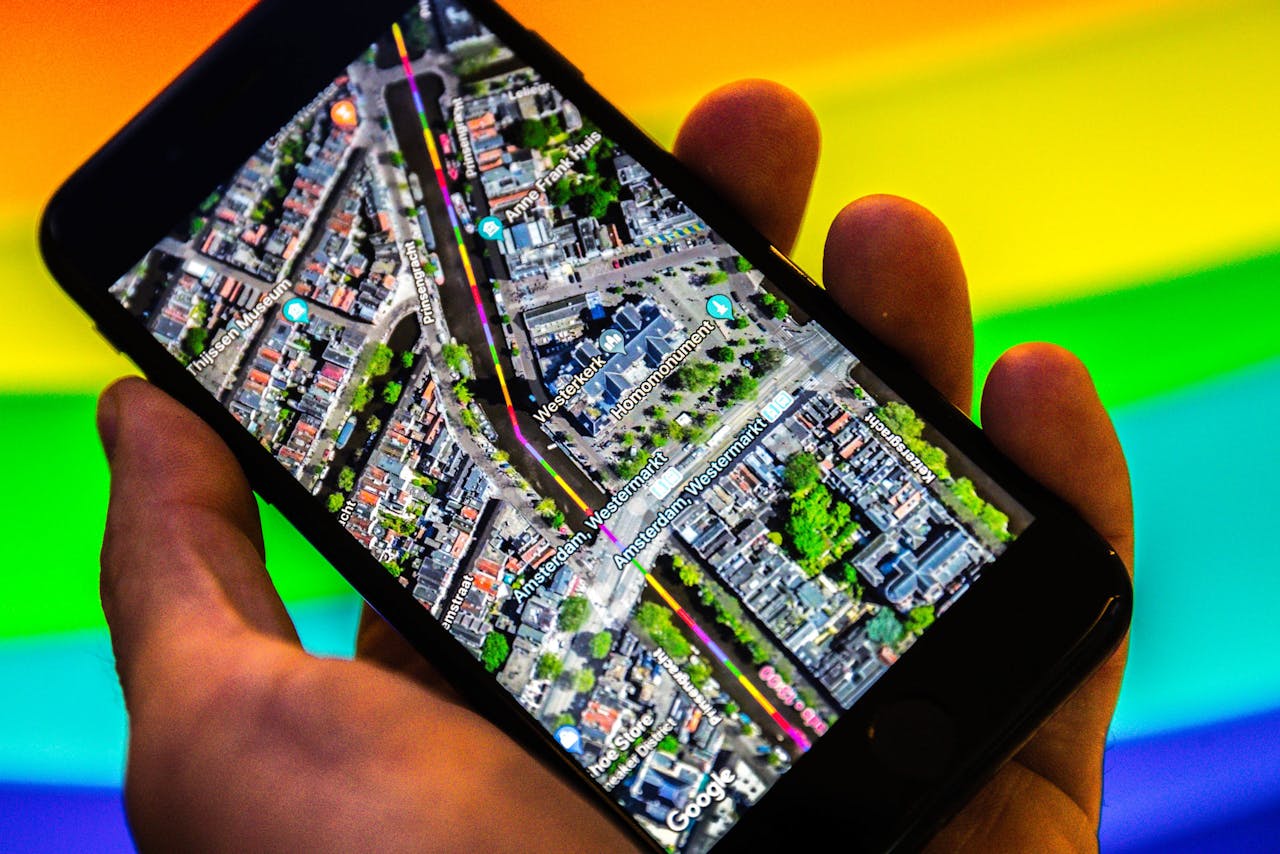 Een smartphone met Google Maps. De zoekgigant geeft met regenboogkleuren de route van de Canal Parade in Amsterdam aan tijdens de Gay Pride 2018.