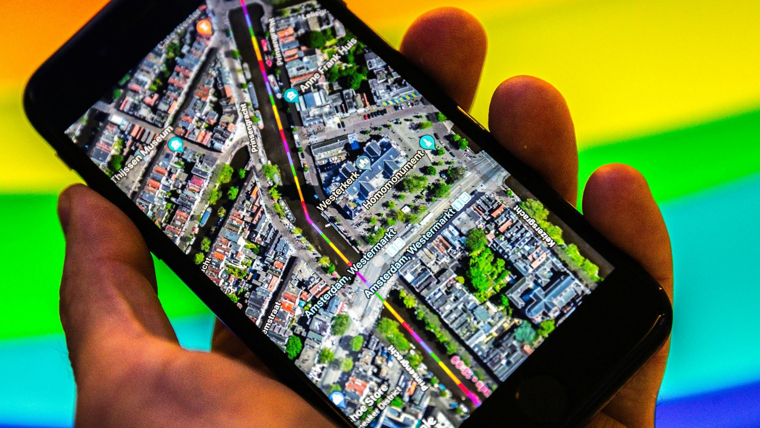 Een smartphone met Google Maps. De zoekgigant geeft met regenboogkleuren de route van de Canal Parade in Amsterdam aan tijdens de Gay Pride 2018. 