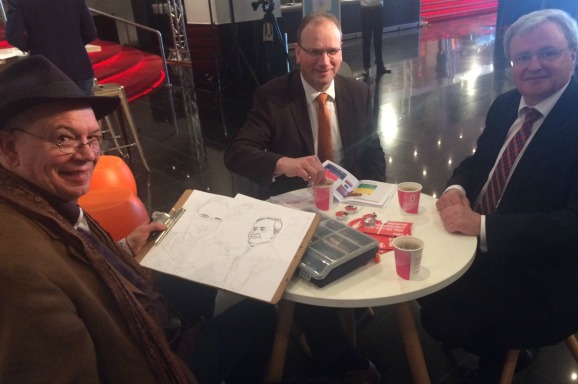 Cartoonist tekent snel FNV-leider Heerts (midden) en MKBNL-voorman Van Straalen. Foto BNR / Elfanie toe Laer