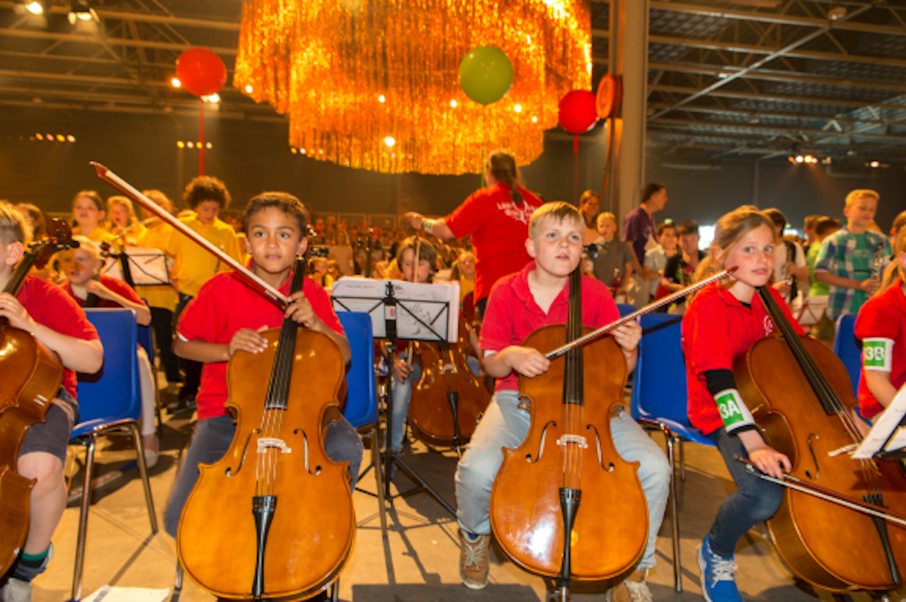 Kinderen musiceren tijdens de tweede editie van het eindconcert van Kinderen Maken Muziek, juni dit jaar. Dit initiatief biedt zoveel mogelijk kinderen de mogelijkheid in aanraking te komen met een muziekinstrument en samen muziek te maken. Bij dit concert was ook koningin Máxima aanwezig.