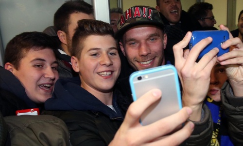 Lukas Podolski (R) komt aan op het vliegveld in Milaan. EPA