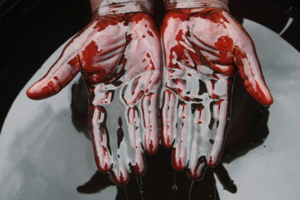 Een man bedekt zijn handen in ruwe olie. EPA