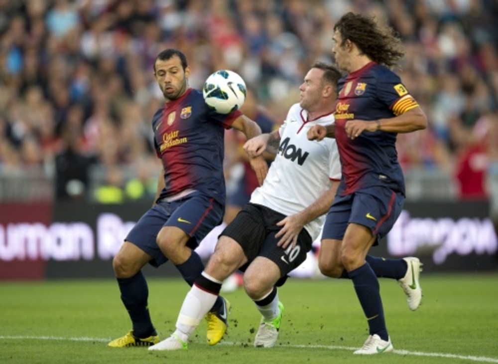 Wayne Rooney (M) van Manchester United in duel met Javier Mascherano (L) en Carles Puyol (R) van Barcelona. EPA 