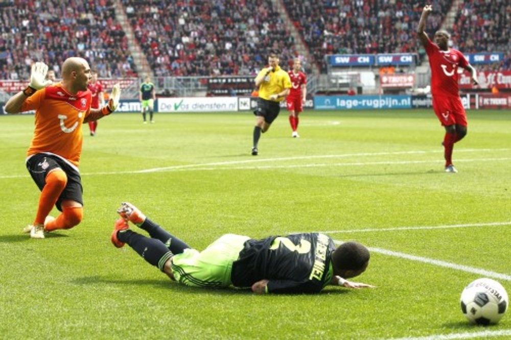 Gregory van der Wiel (M) van Ajax wordt neergelegd door keeper Nicolay Mihaylov (L) van FC Twente.