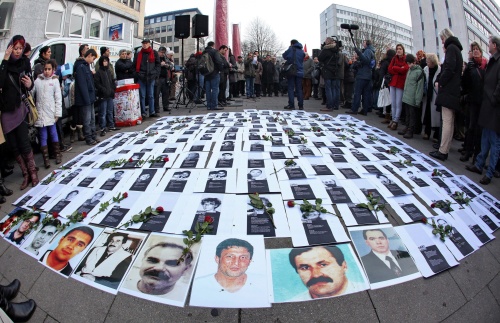 Foto's van slachtoffers van de 'dÃ¶nermoorden' liggen zaterdag op straat voordat er een stille tocht wordt gehouden in Hamburg. EPA