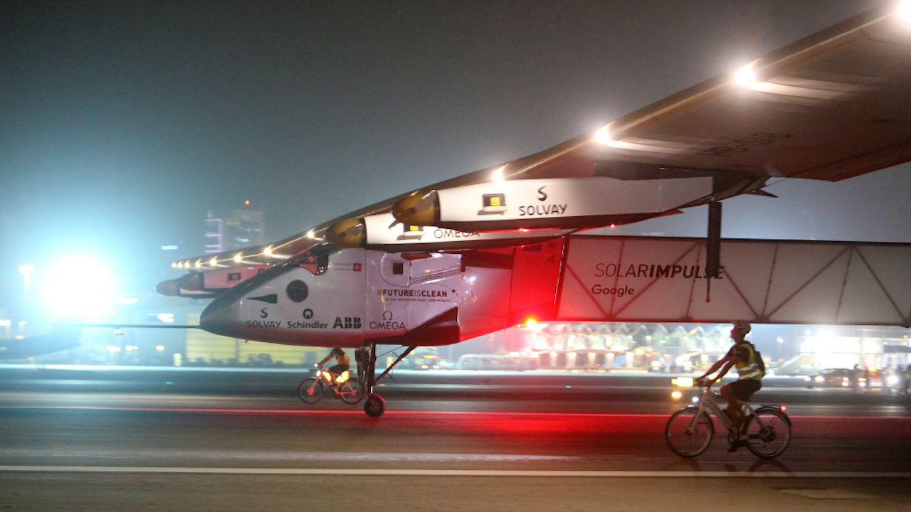 Het vliegtuig Solar Impulse II komt aan op Al Bateen Executive Airport in Abu Dhabi. De twee fietsers moeten het vliegtuig na de landing opvangen en afremmen. (Foto: ANP)