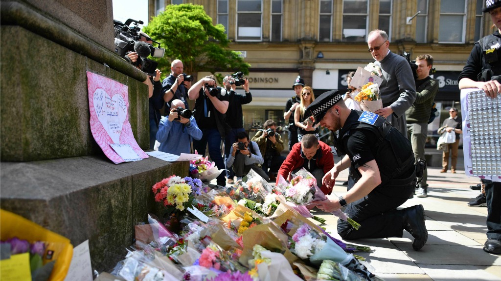 Politieagenten herschikken bloemen die op St Ann's Square in Manchester zijn neergelegd ter nagedachtenis van de slachtoffers van de aanslag gisteravond bij Manchester Arena. Foto ANP