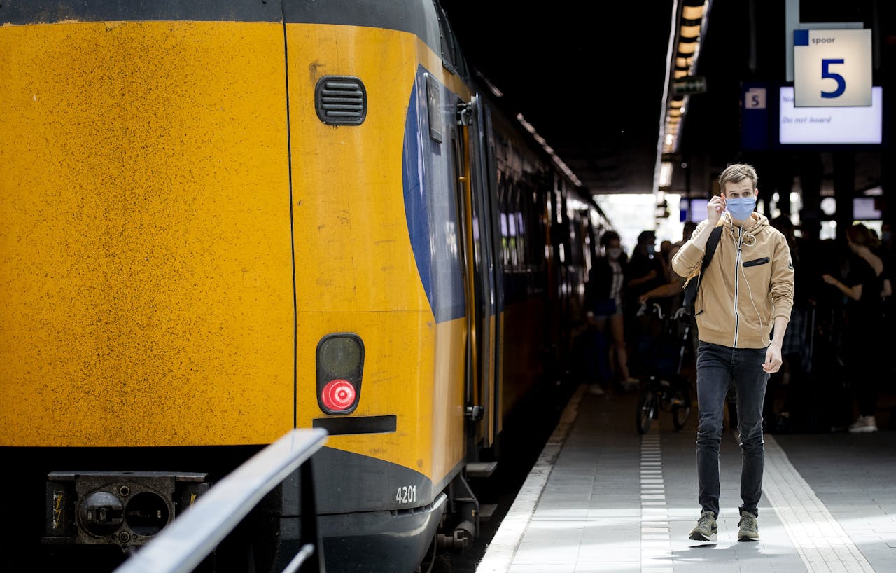 Een reiziger met mondkapje op Den Haag Centraal Station.