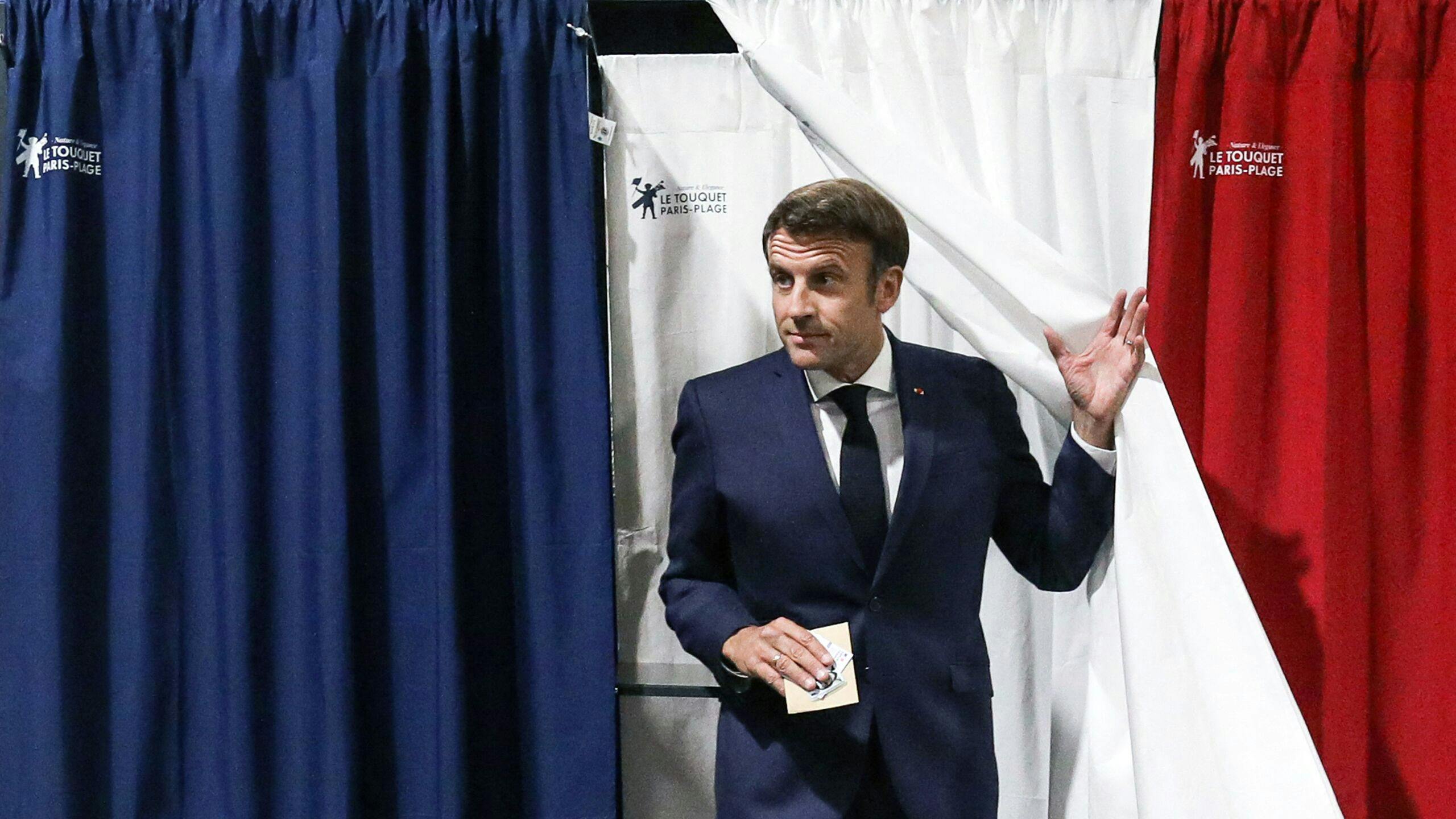 President Macron in het stemhokje.