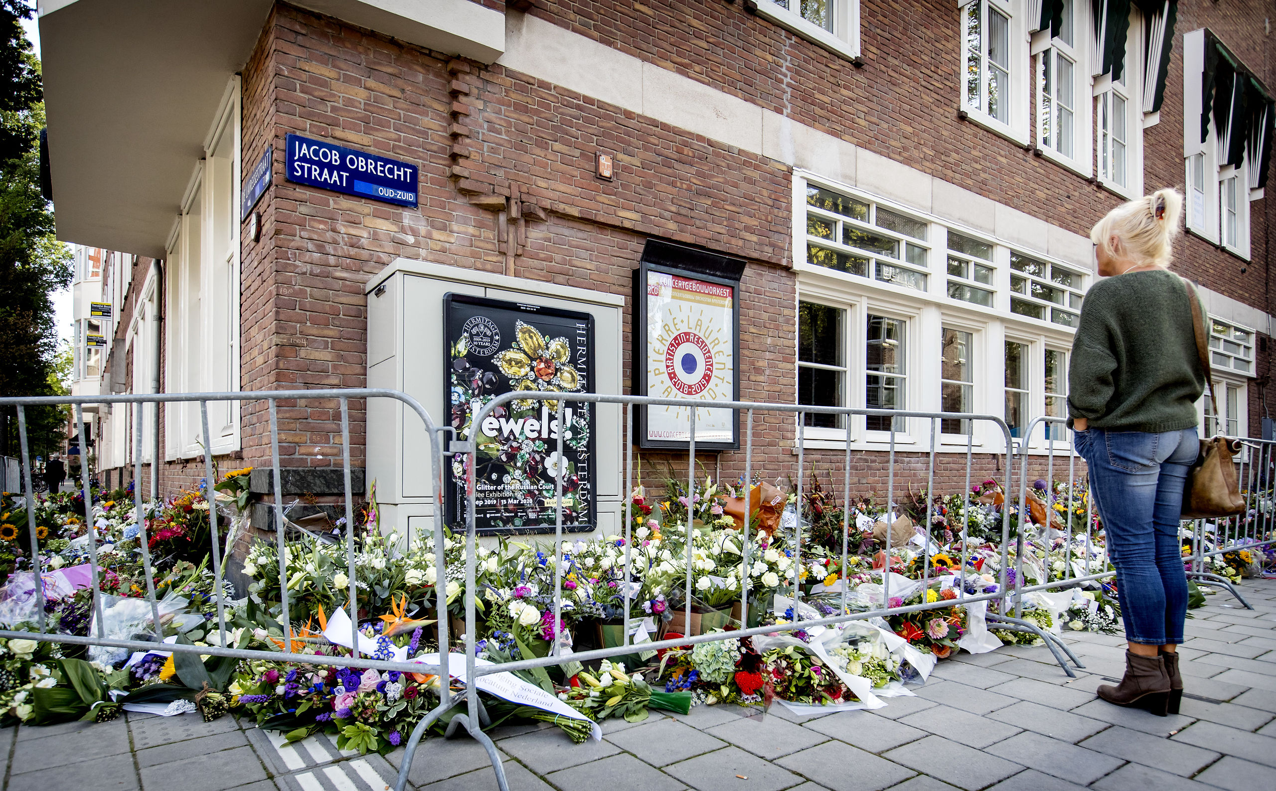 Een passant kijkt bij de bloemen die zijn neergelegd bij het kantoor van de doodgeschoten advocaat Derk Wiersum. 