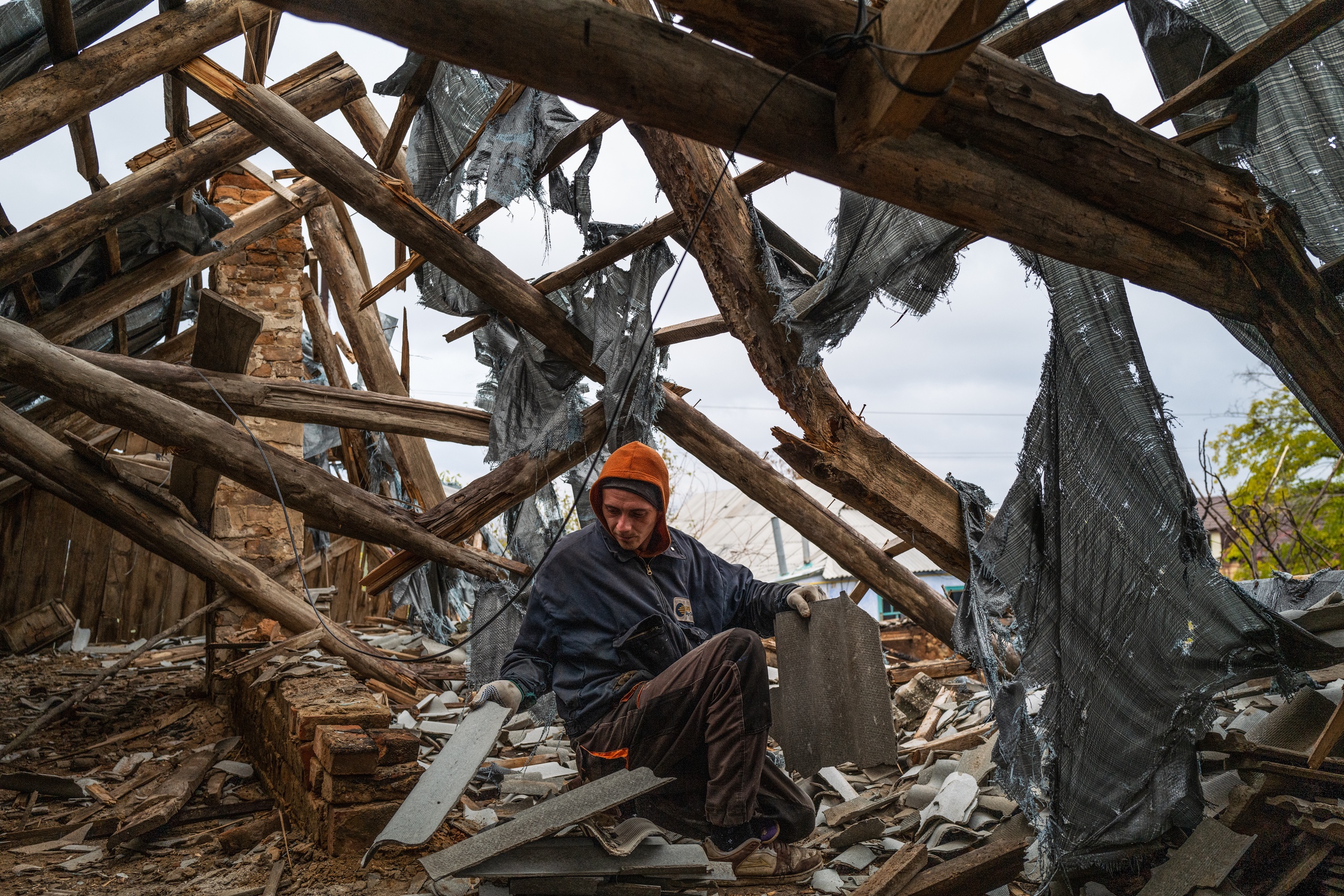 Een arbeider verzamelt hout en dakmaterialen uit een verwoeste woning in het recent door de Oekraïners heroverde dorp Velyka Oleksandrivka in Cherson.