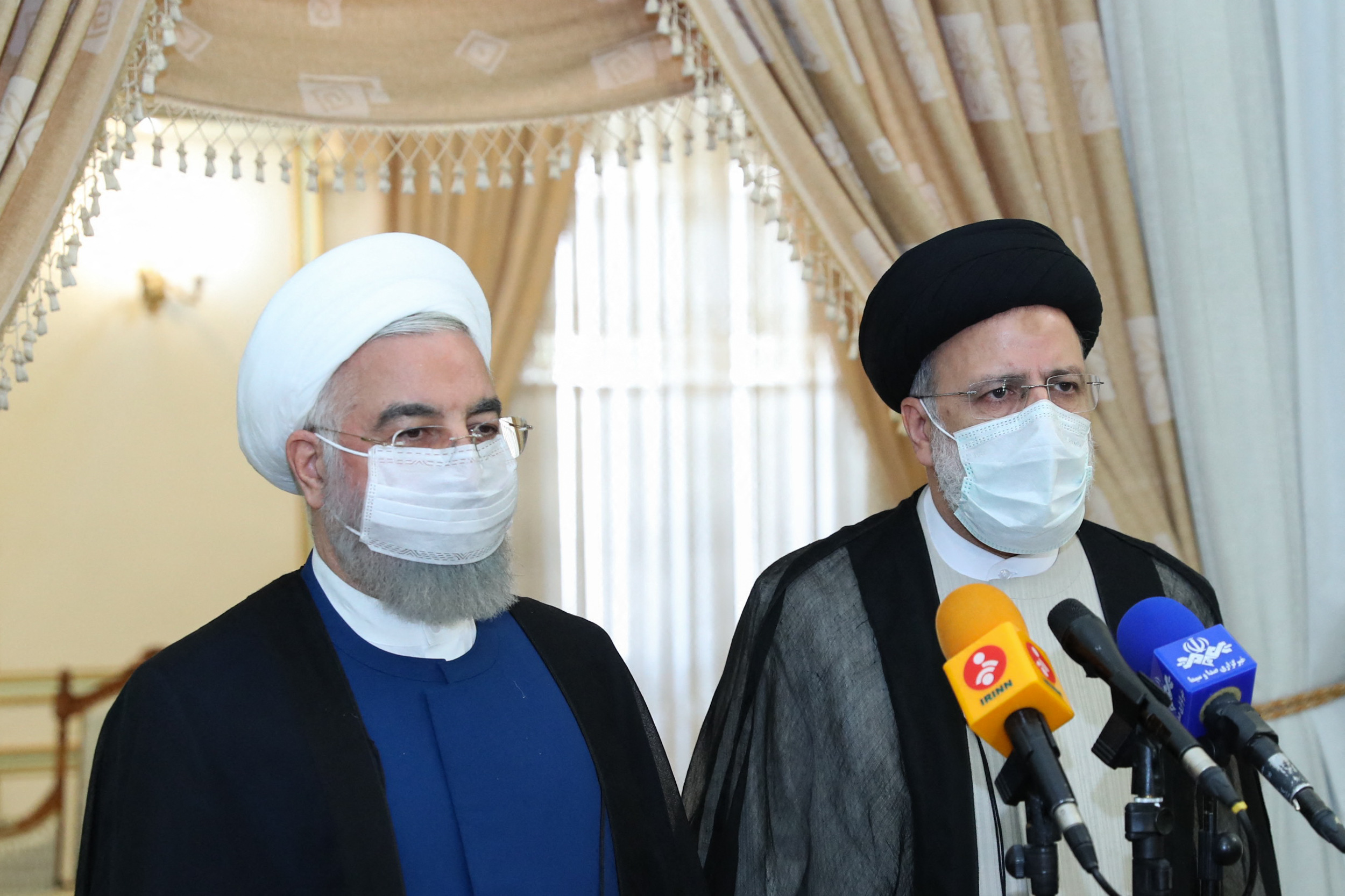 Vertrekkende president Hassan Rouhani (links) naast Ebrahim Raisi tijdens een persconferentie. 