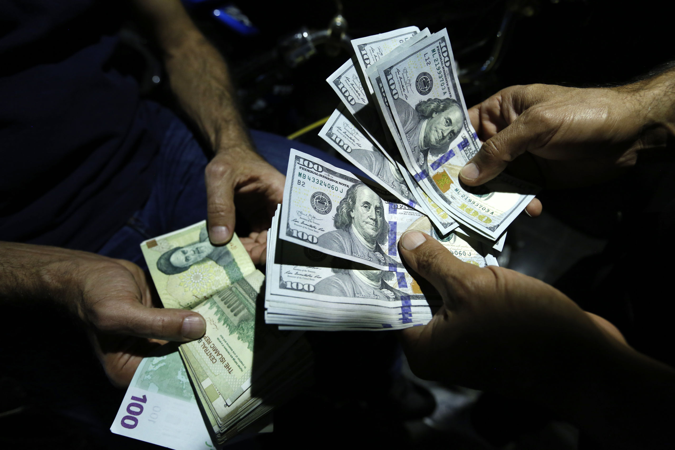 Iraans rial's en Amerikaanse dollars worden gewisseld in Teheran.