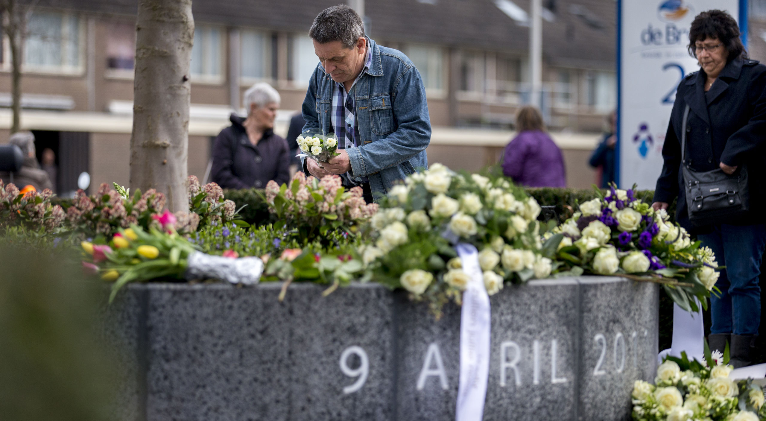 Mensen leggen bloemen bij het monument ter nagedachtenis aan de slachtoffers van het schietdrama in winkelcentrum de Ridderhof.