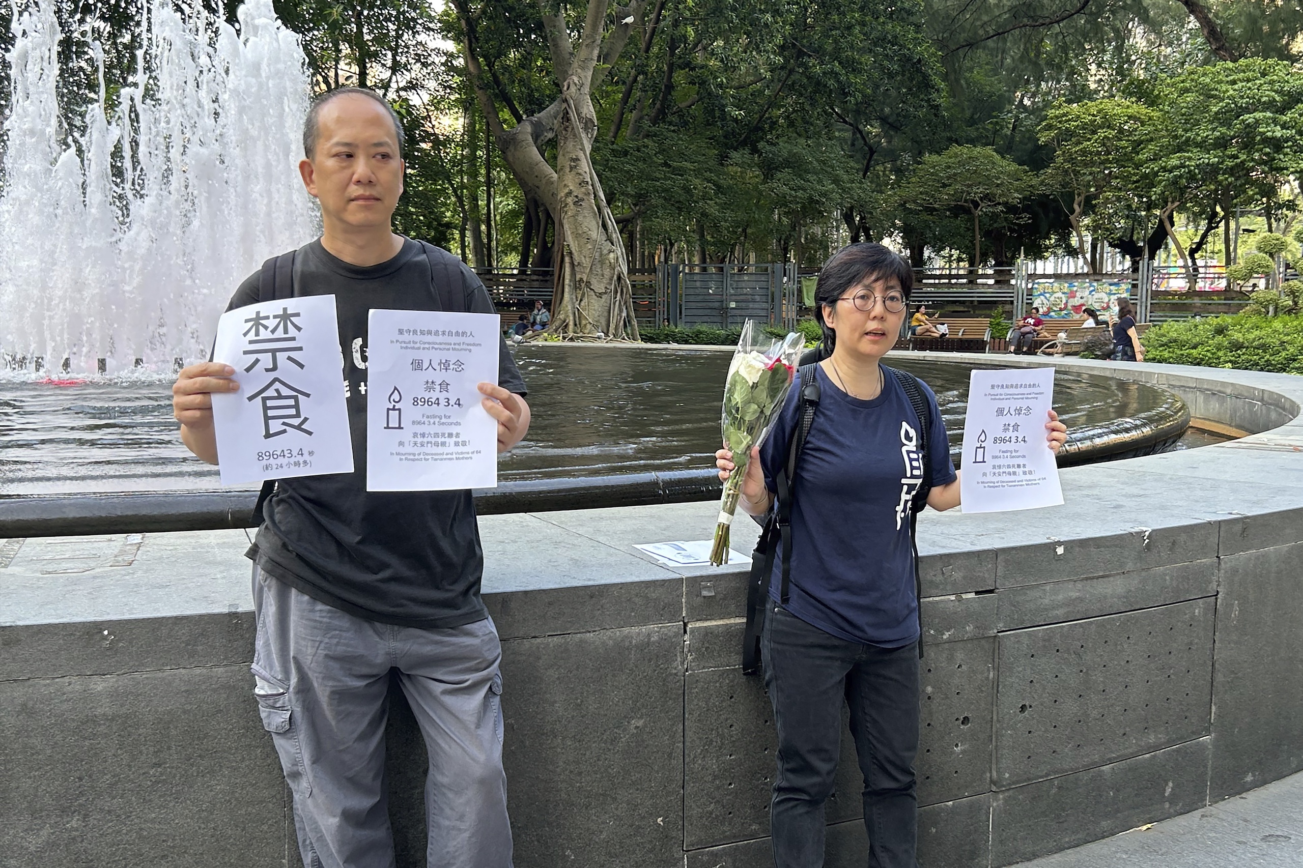 Aan de vooravond van de 34e verjaardag van China's onderdrukking van het Tiananmen Plein, houden Tiananmen activisten Kwan Chun-pong (l) en Lau Ka-yee (r) papieren omhoog met het woord Fasting en details van hun plan om ongeveer een dag te vasten bij de ingang van Hong Kong's Victoria Park als onderdeel van hun herdenking op zaterdag 3 juni 2023. Het tweetal werd kort daarop weggevoerd door de politie. 