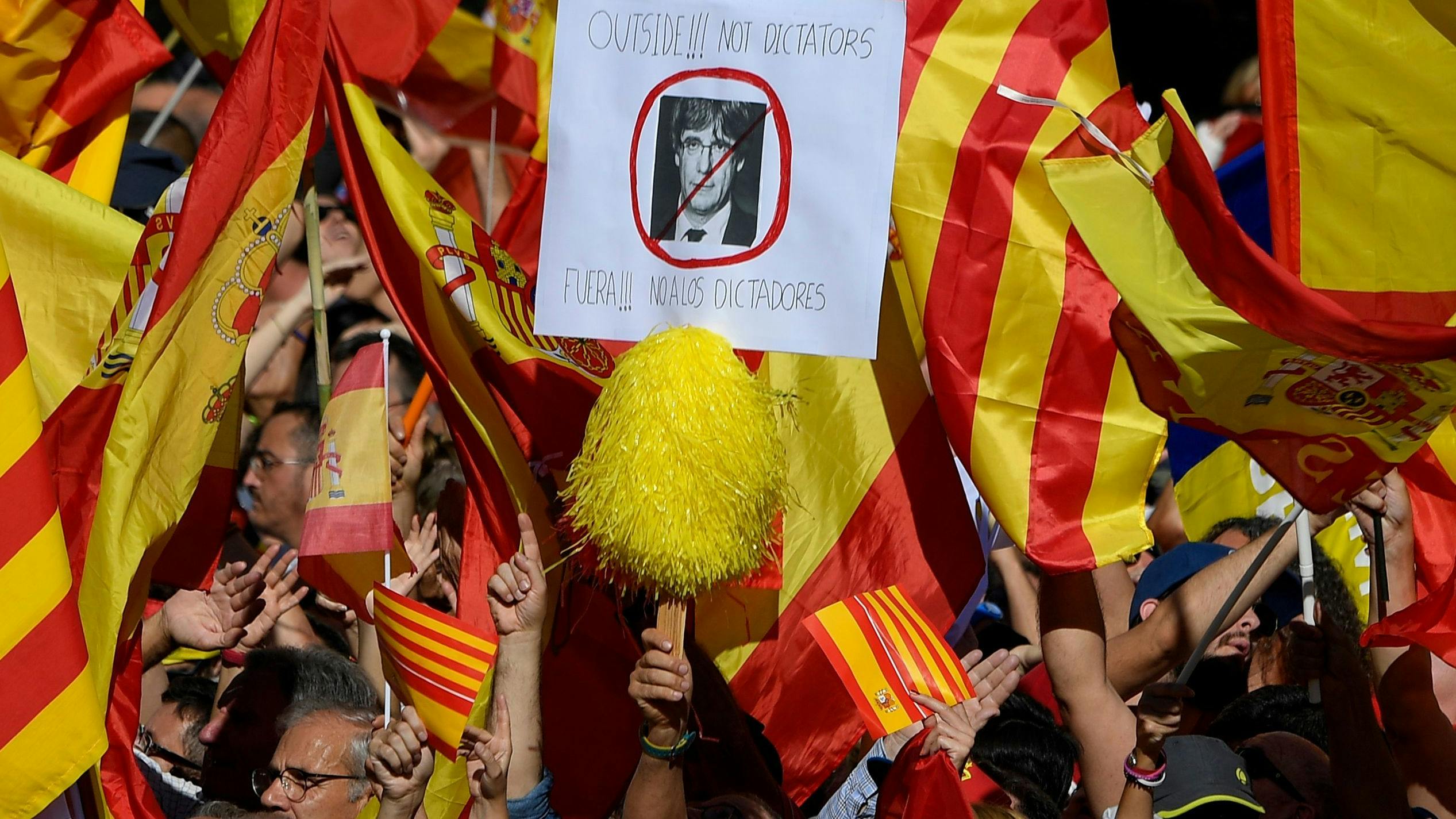 Tijdens een demonstratie van voorstanders van Spaanse eenheid, gisteren in Barcelona, houdt een betoger een bord omhoog met het portret van Puigdemont en de tekst: 'weg met de dictators'. 
