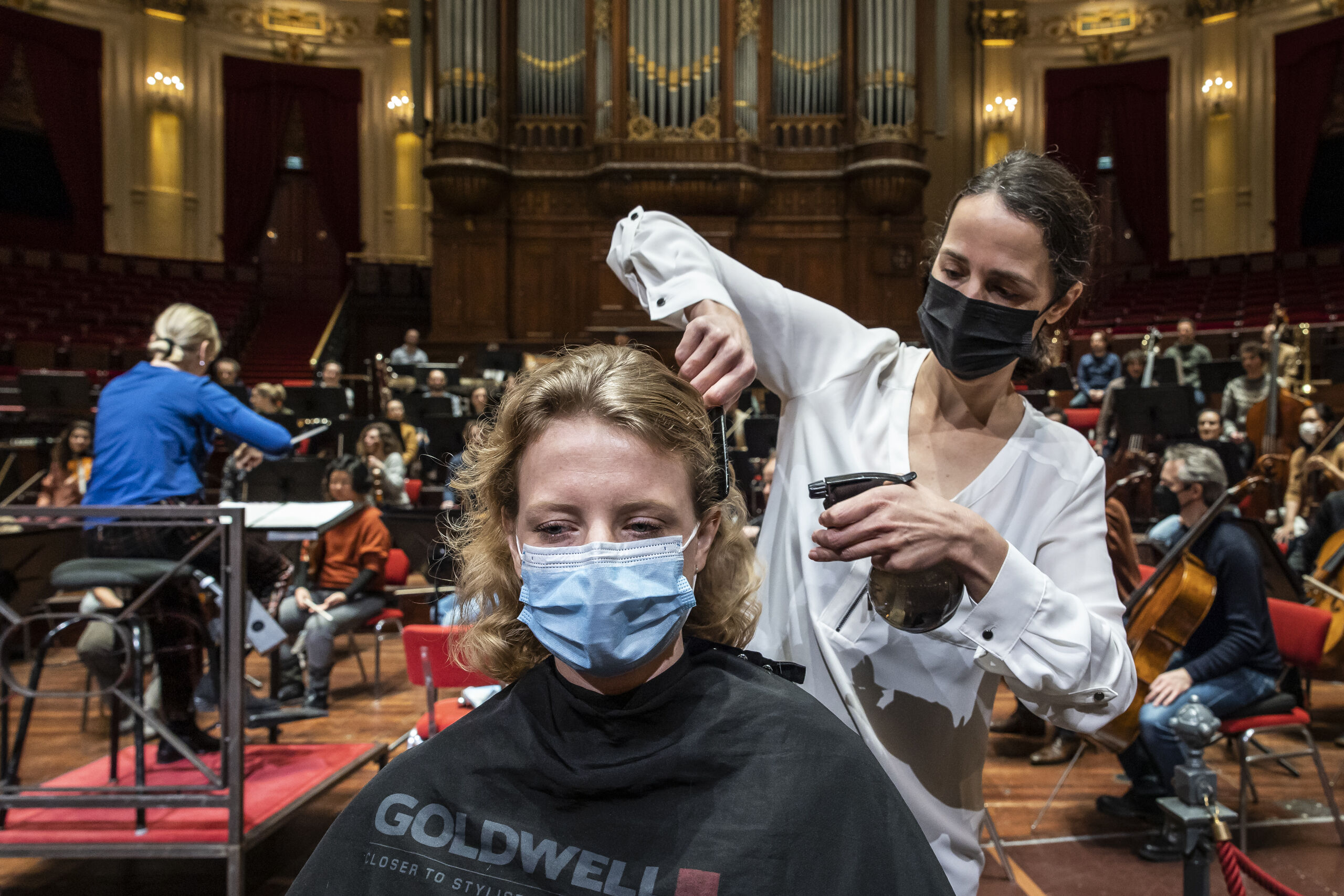 In het Concertgebouw in Amsterdam knippen kappers klanten op het podium terwijl het Concertgebouworkest repeteert, Het is een actie tegen het coronabeleid van de overheid. 
