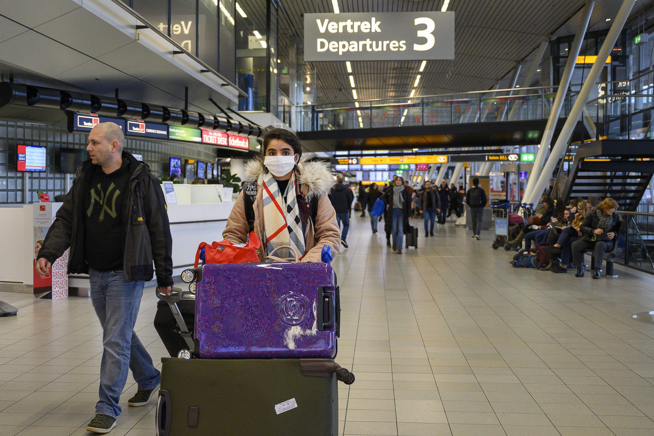 Reizigers op Schiphol dragen een mondkapje. 