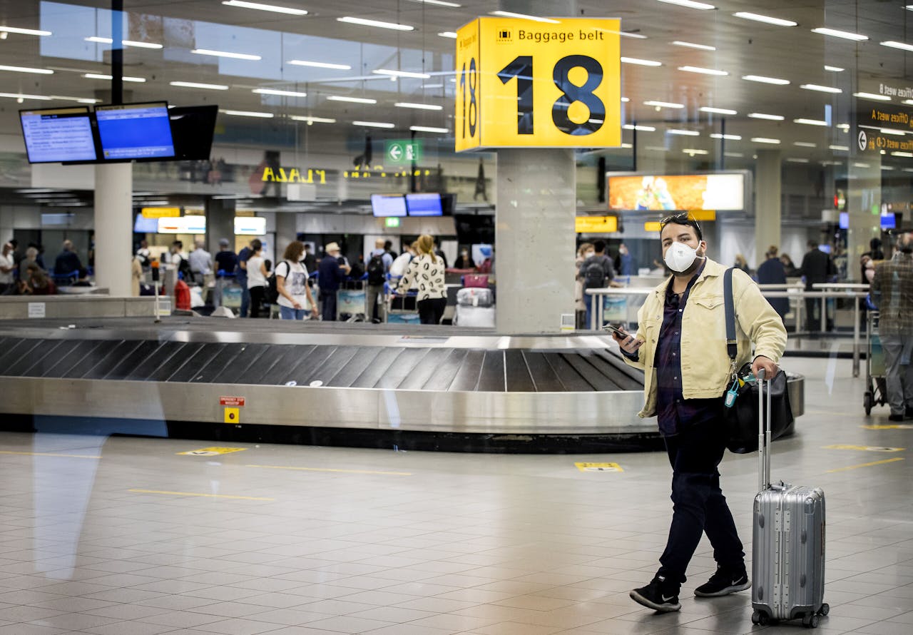 Reizigers met mondkapjes op luchthaven Schiphol.