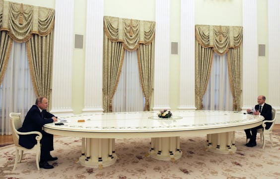 De Russische president Vladimir Poetin (links) in gesprek met de Duitse bondskanselier Olaf Scholz (zes meter tegenover Poetin).