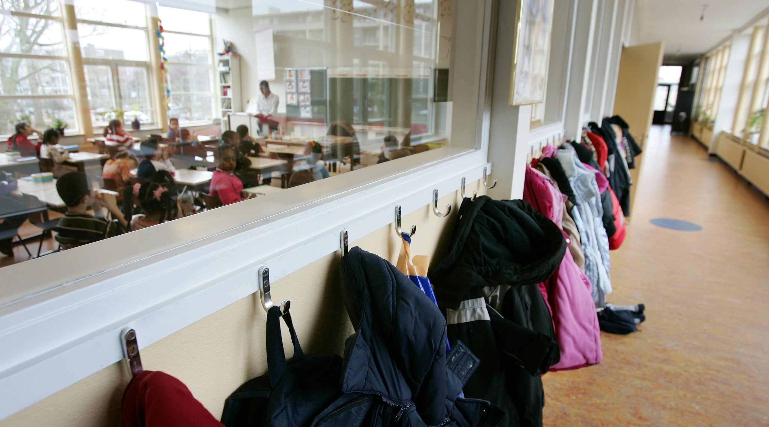 Gang met jassen en leerlingen in klaslokaal van de Petrus Donders school in Den Haag.