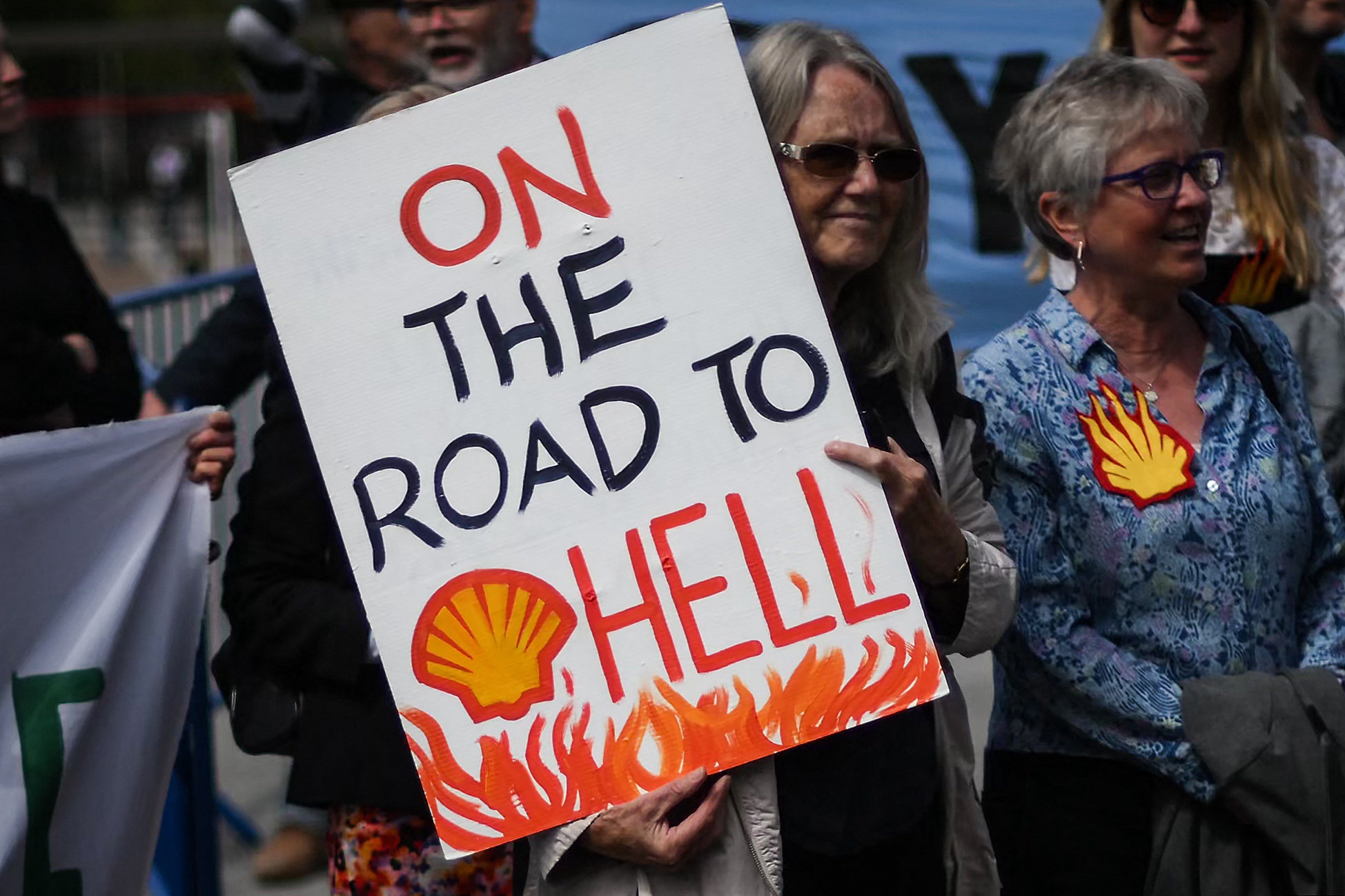 A climate activist holds a banner as he demonstrates outside ExCeL in London during the annual general meeting of oil and gas multinational Shell on May 23, 2023.